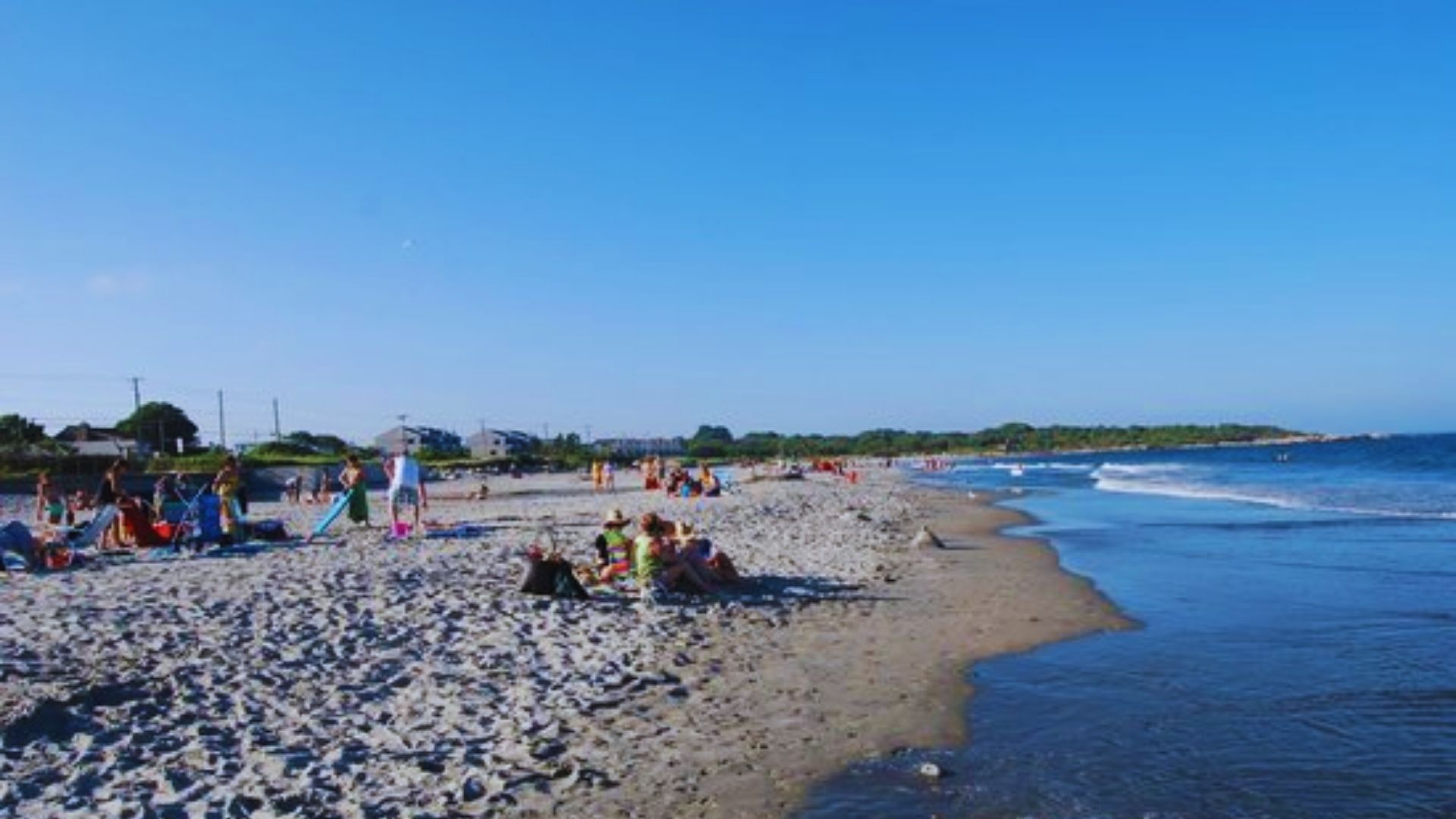 Beachgoers bask in the sun and enjoy leisure activities on a bright, sunny day.