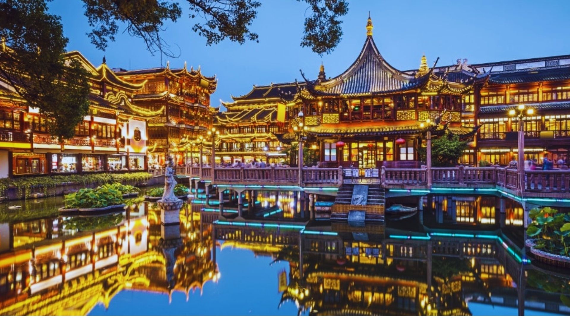 Traditional Chinese buildings in Shanghai illuminated at night, showcasing intricate architecture against a dark sky.