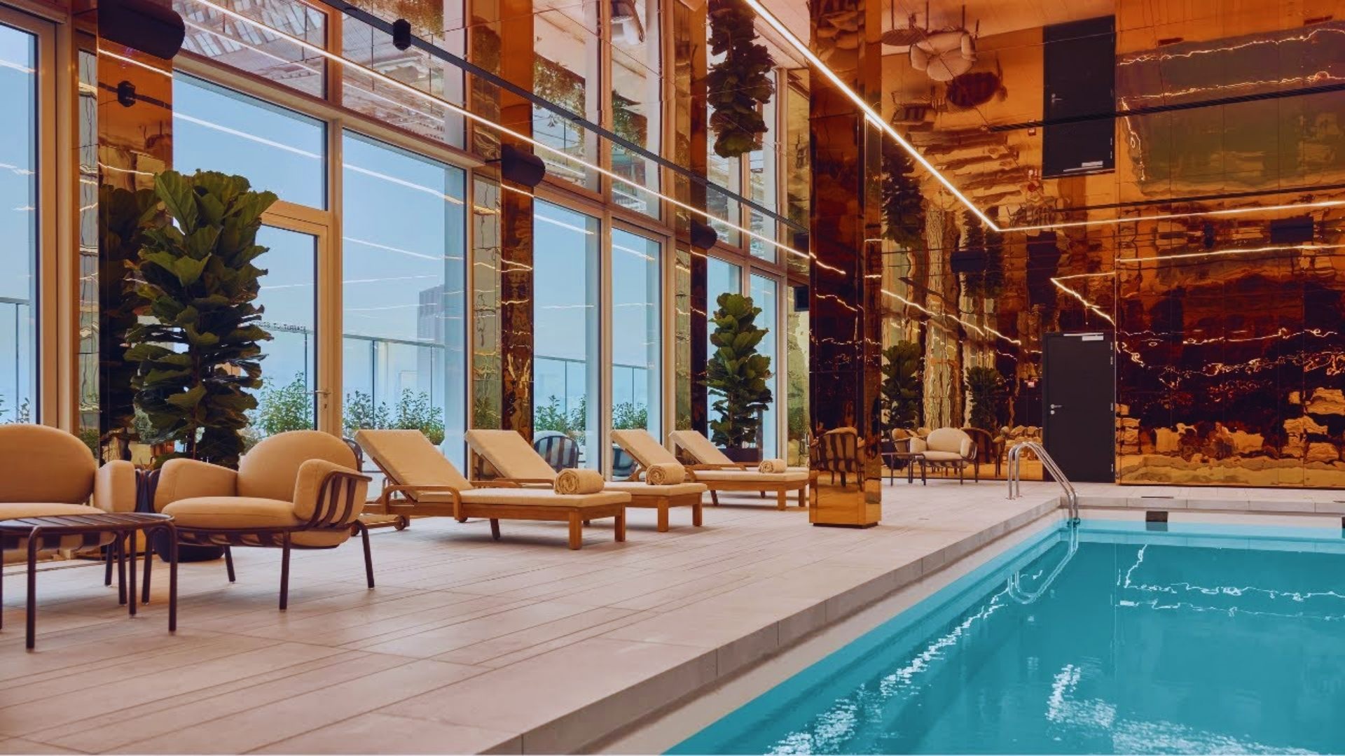 The hotel pool is enclosed by transparent glass walls, providing a modern and open atmosphere.