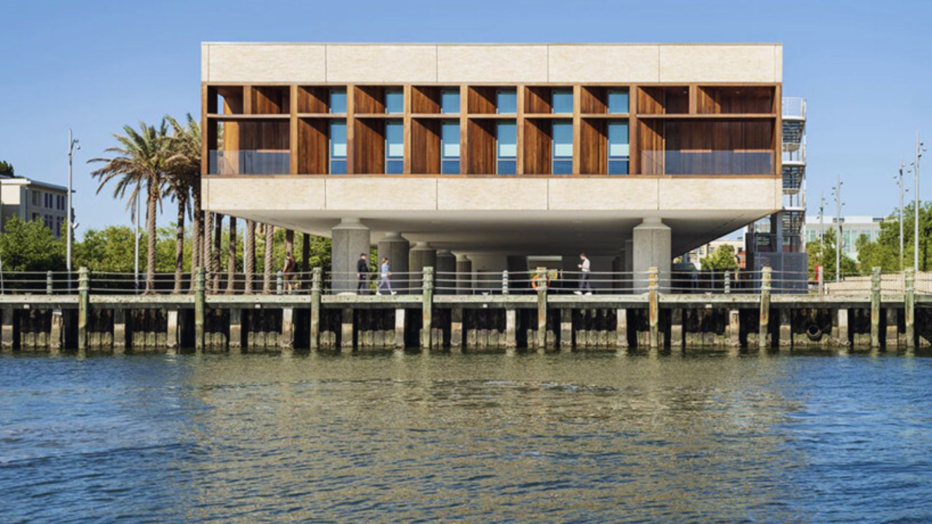 A building with wooden panels stands beside the water, reflecting its structure in the calm surface.
