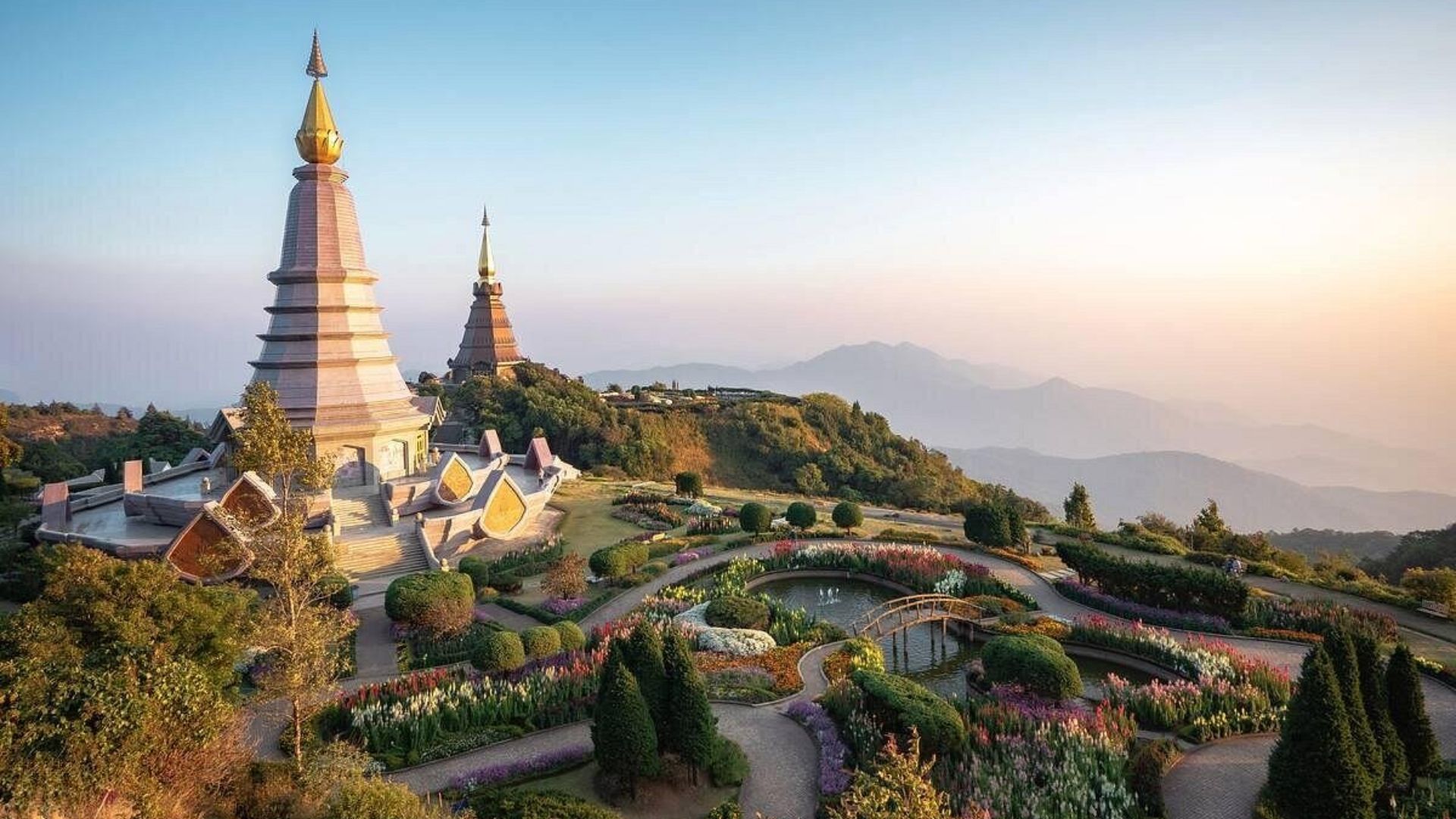 Scenic view of beautiful pagodas perched atop a mountain, surrounded by lush greenery and a clear blue sky.