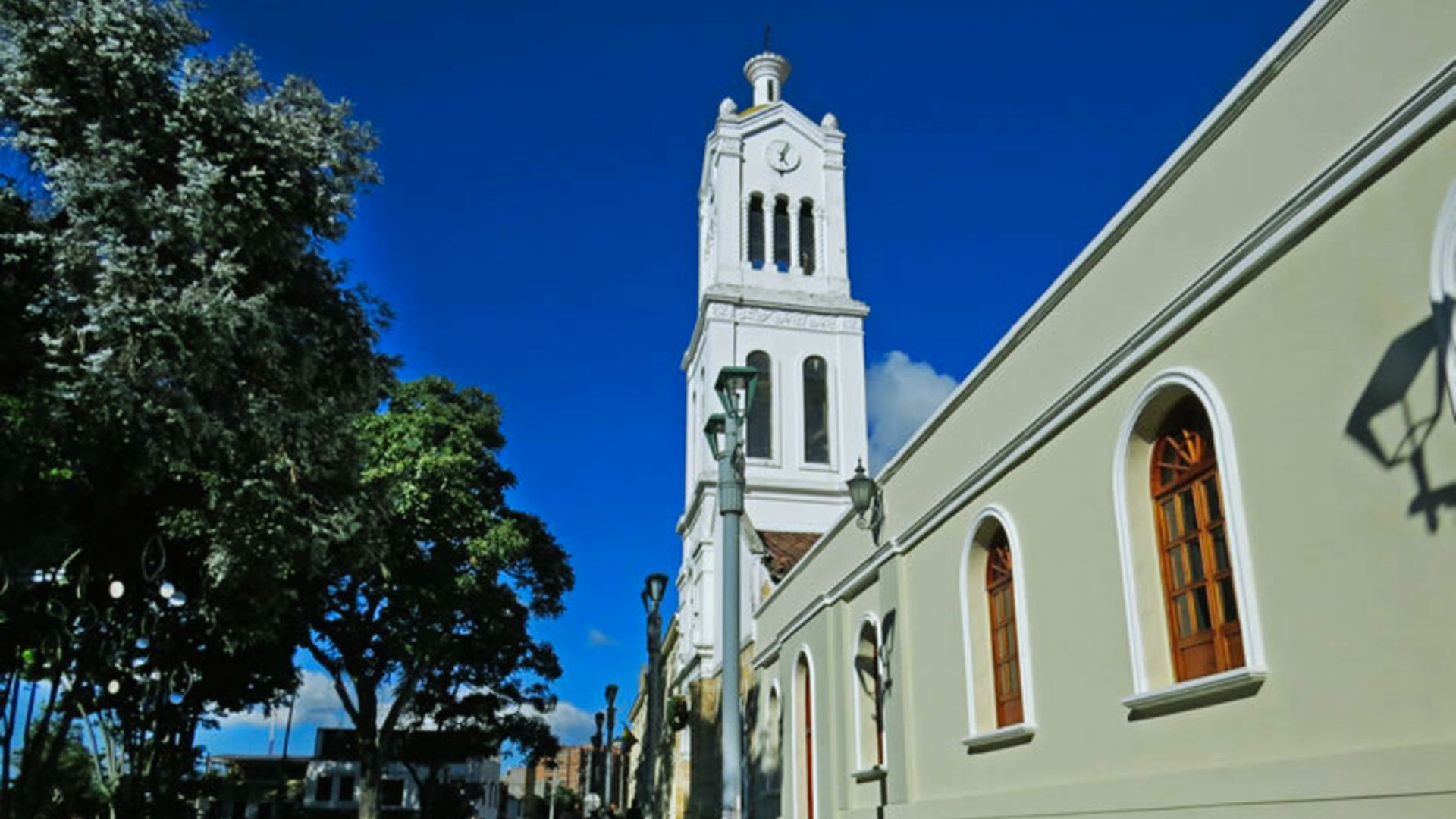 A church featuring a tall steeple and a prominent clock tower against a clear blue sky.
