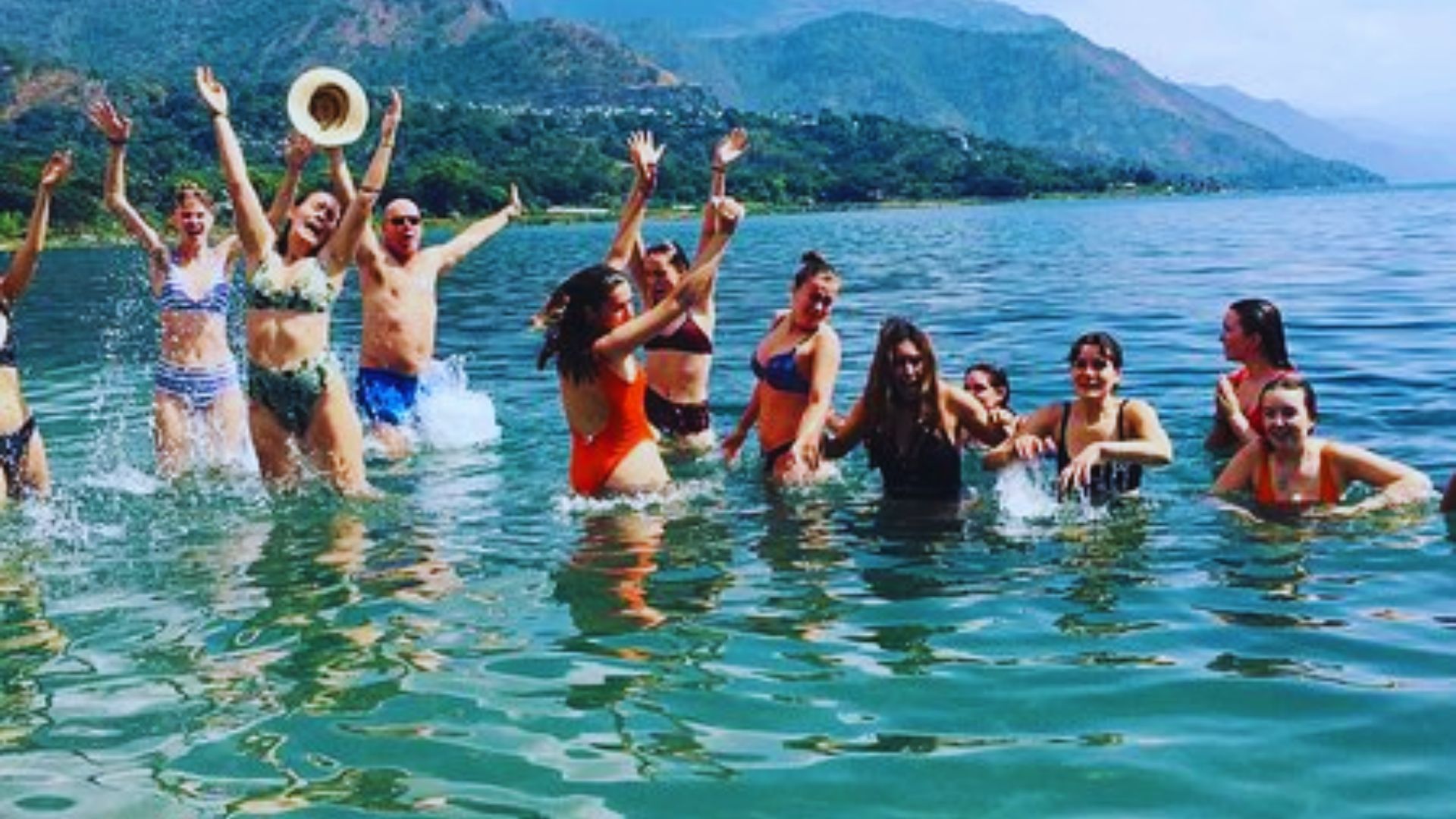 A group of people in the water, joyfully raising their arms in celebration.