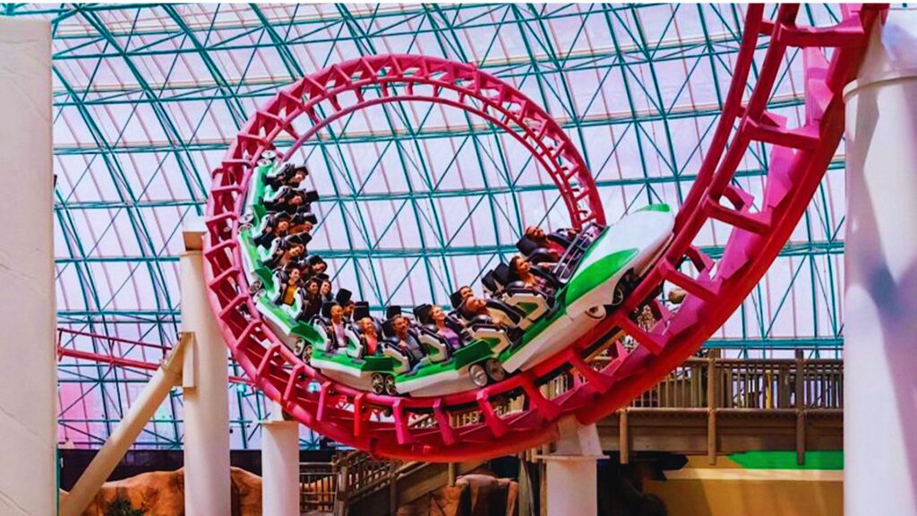 Indoor amusement park featuring a thrilling roller coaster ride with colorful tracks and excited riders.