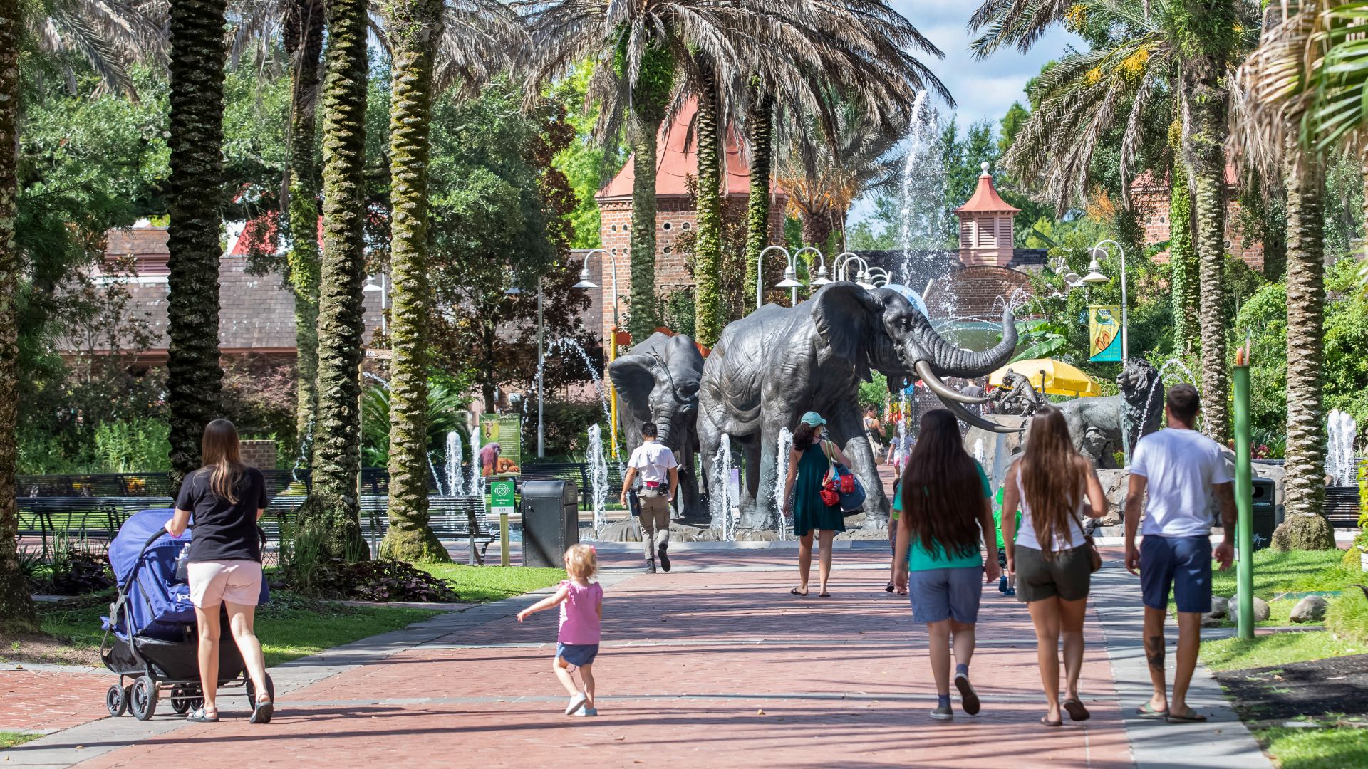 People walking along a path with an elephant statue visible in the background.