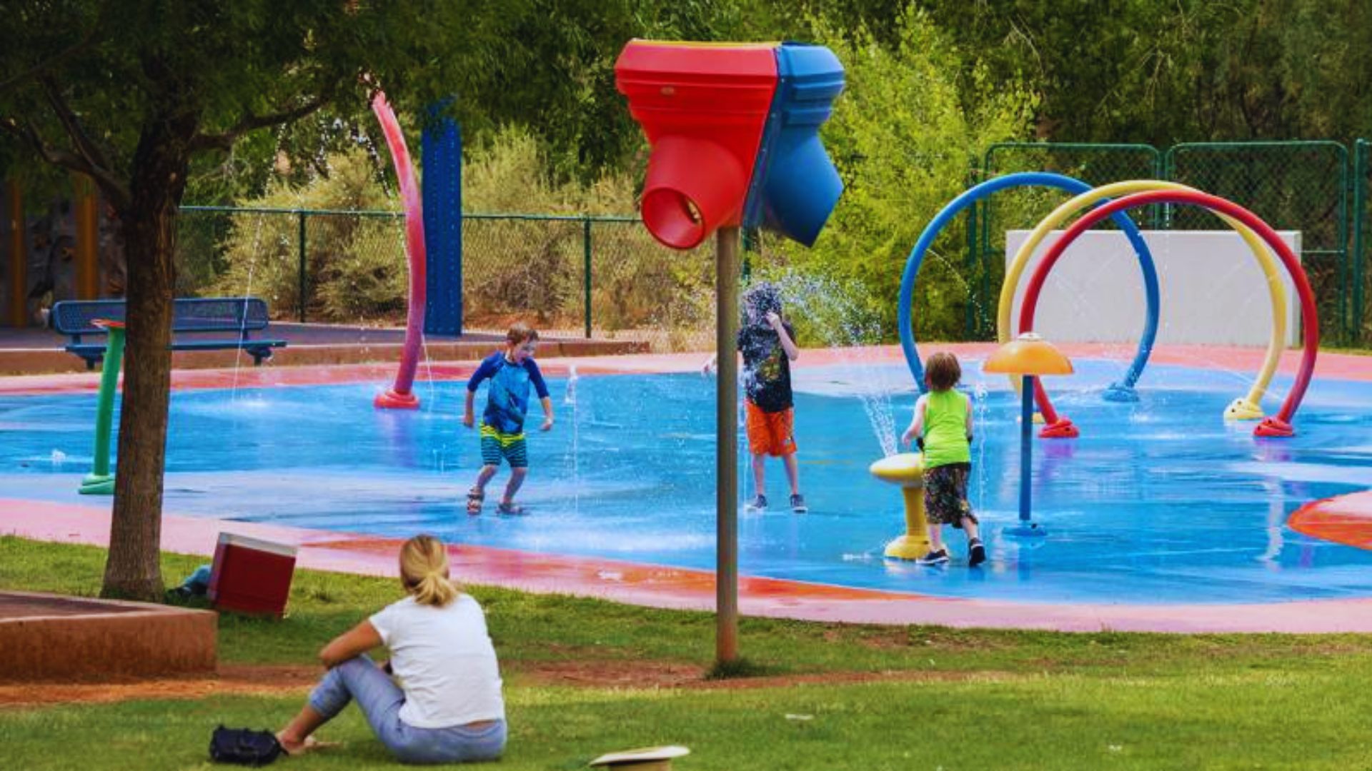 A group of children joyfully playing and splashing water in a vibrant splash park on a sunny day.