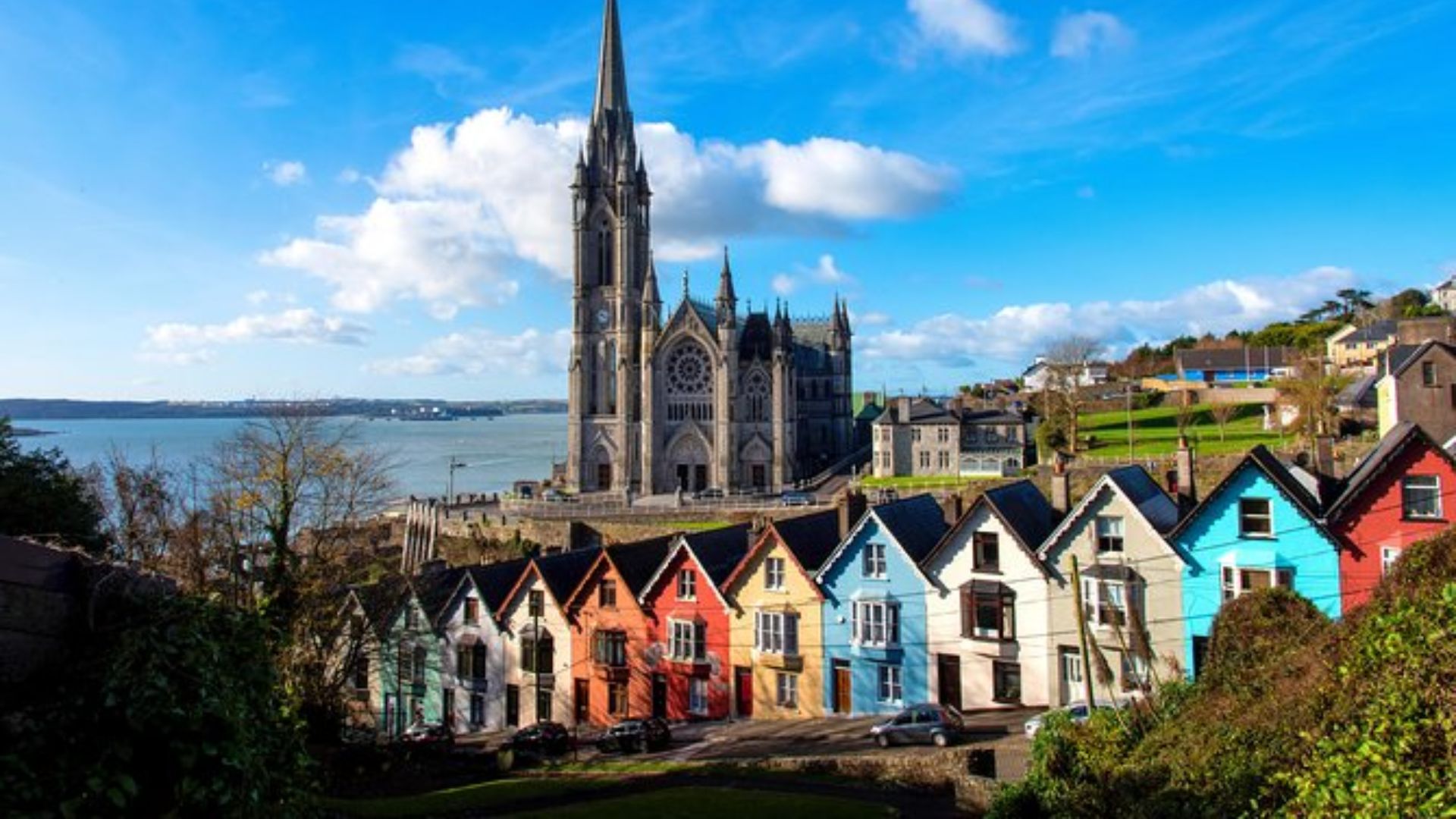 A vibrant row of colorful houses in Ireland, showcasing a mix of bright hues against a clear blue sky.