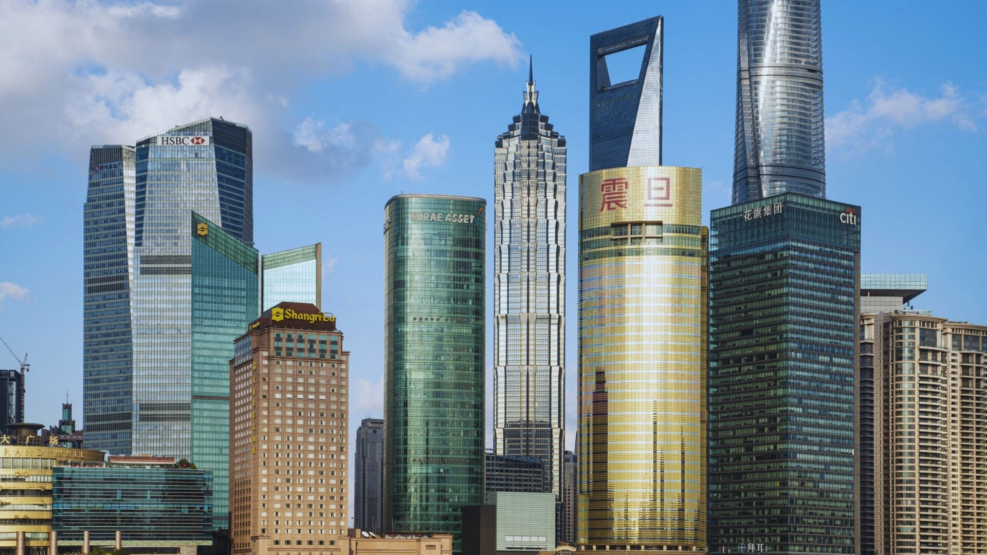 The Shanghai skyline featuring modern skyscrapers and the iconic Oriental Pearl Tower against a clear blue sky.