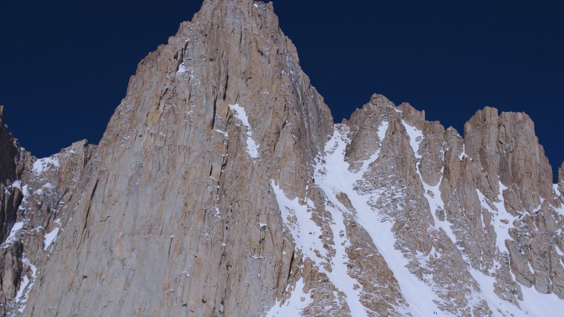 A majestic mountain capped with snow, rising prominently against a clear blue sky.