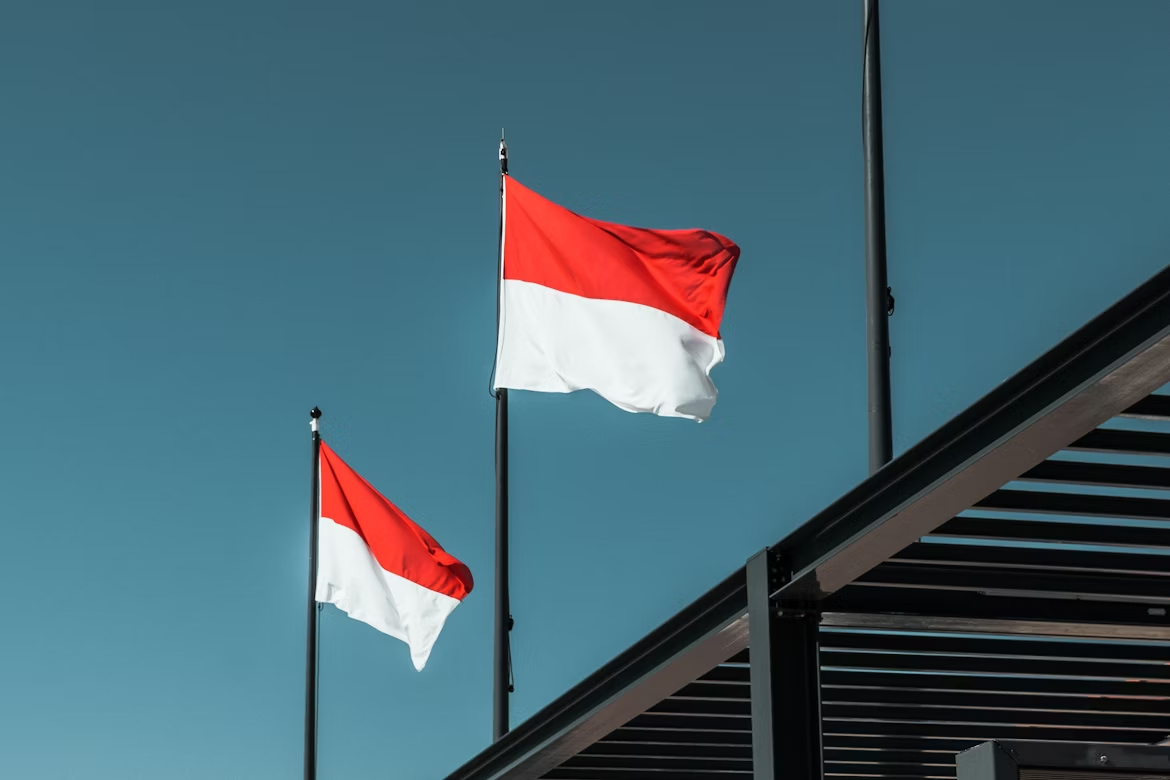. Three red and white flags fluttering in the wind against a clear blue sky