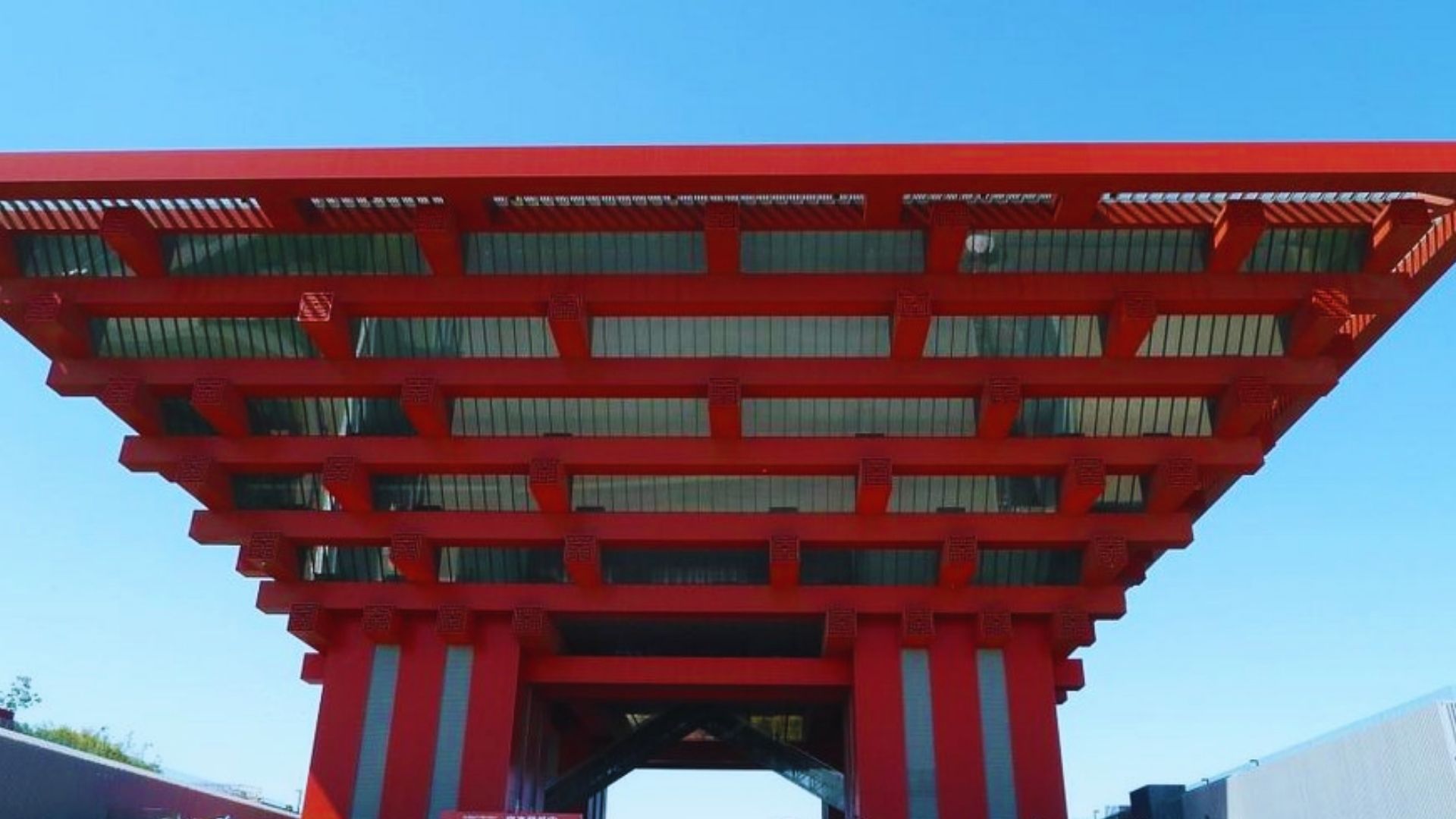 A red building featuring a prominent large red roof against a clear sky.