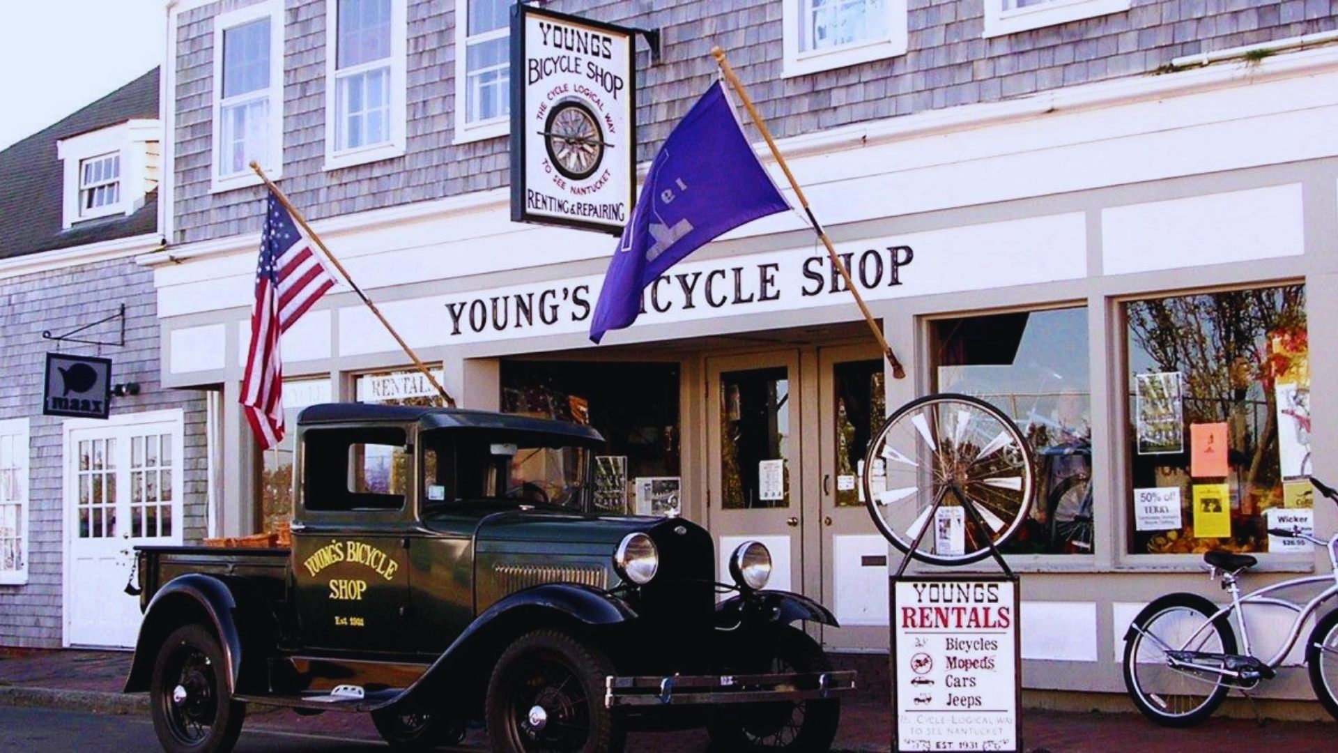 A vintage truck parked in front of a store, showcasing its classic design against a quaint retail backdrop.
