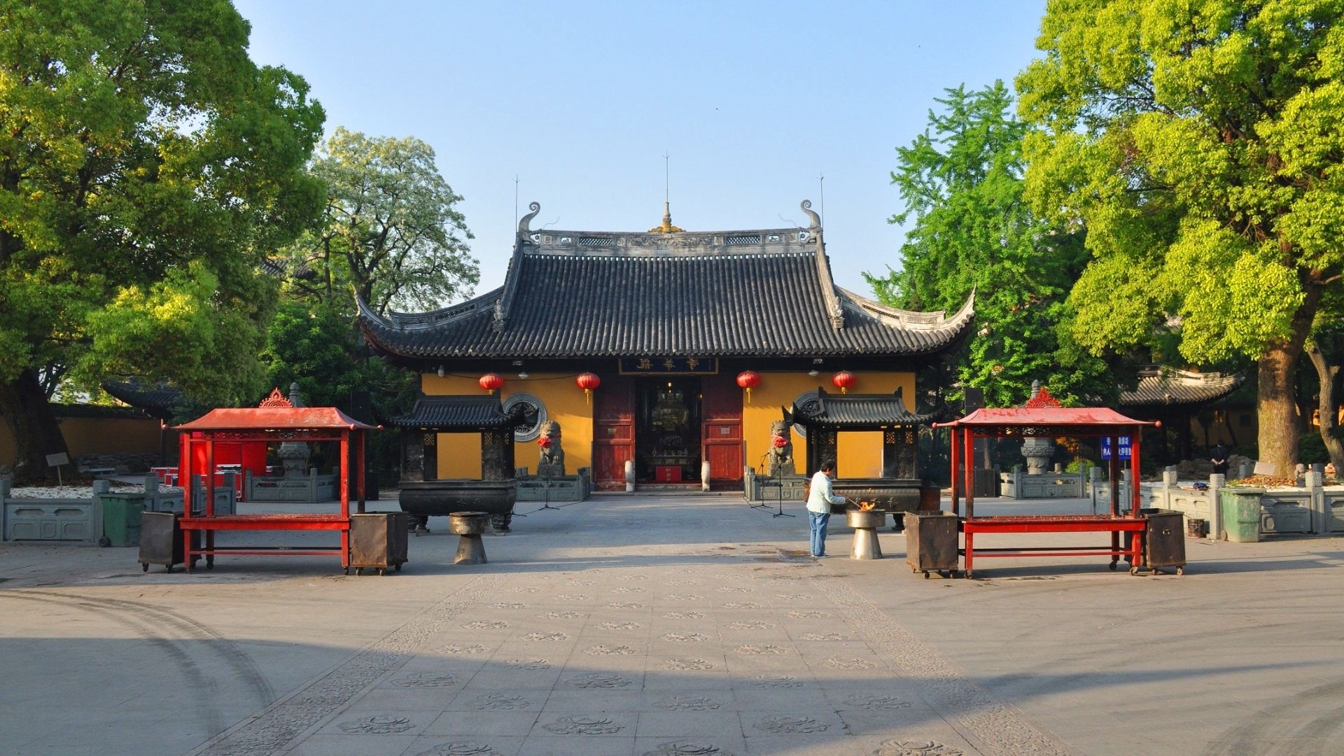 The entrance of a Chinese temple featuring ornate architecture and red benches for visitors to rest.