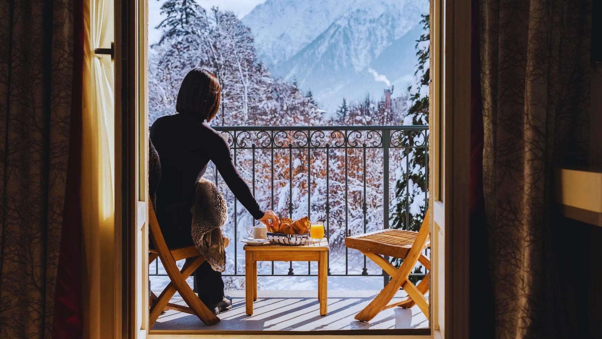 A person seated at a table, enjoying a scenic view of mountains in the background.