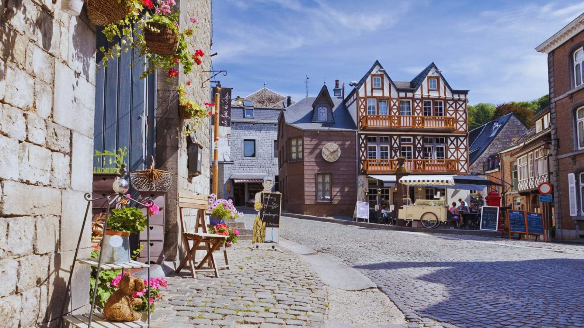 A picturesque cobblestone street in the historic old town of Belgium, lined with charming buildings and vibrant flowers.