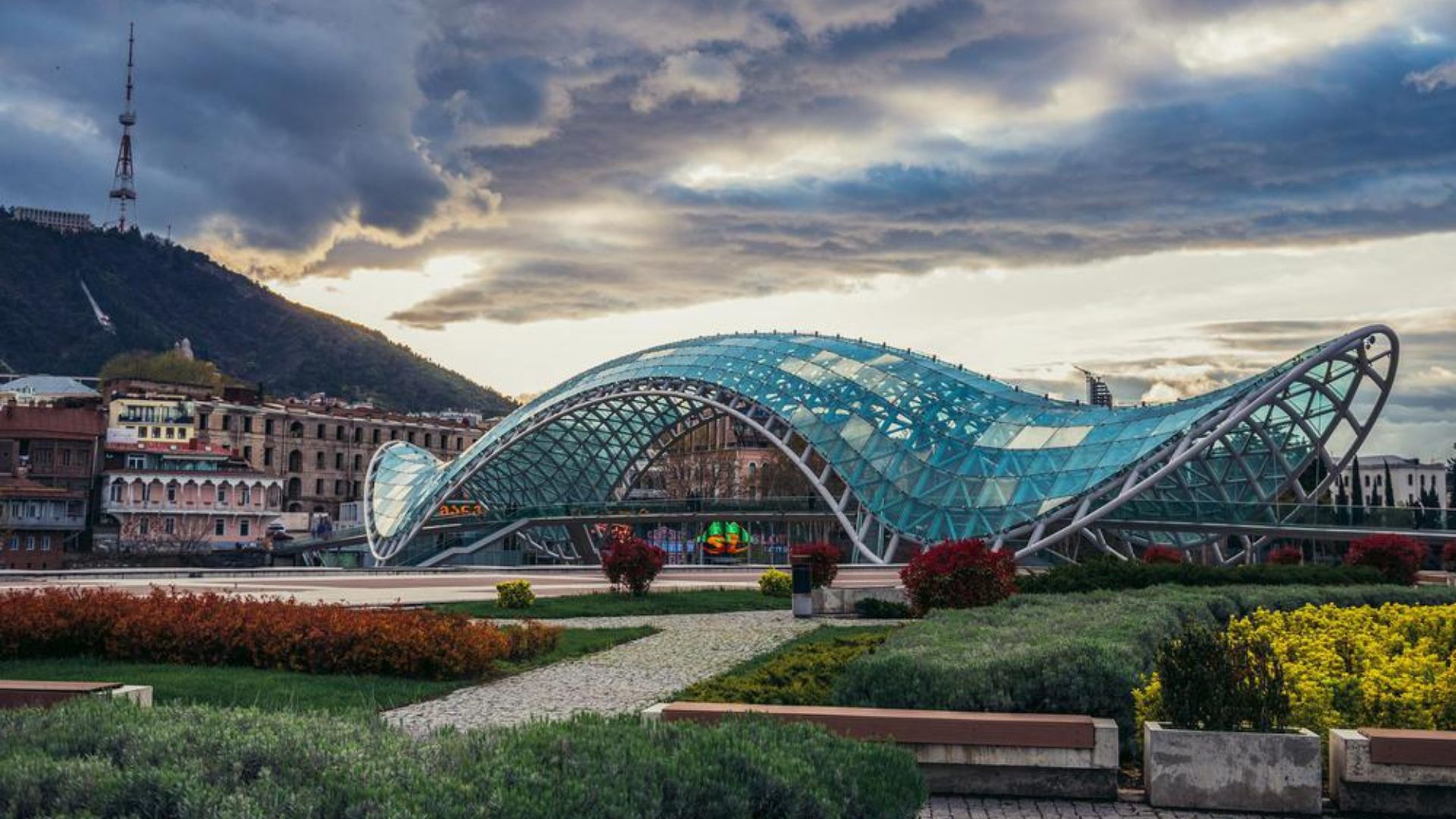 Sunset view of the Tbilisi bridge, silhouetted against a colorful sky, reflecting the city's vibrant atmosphere.