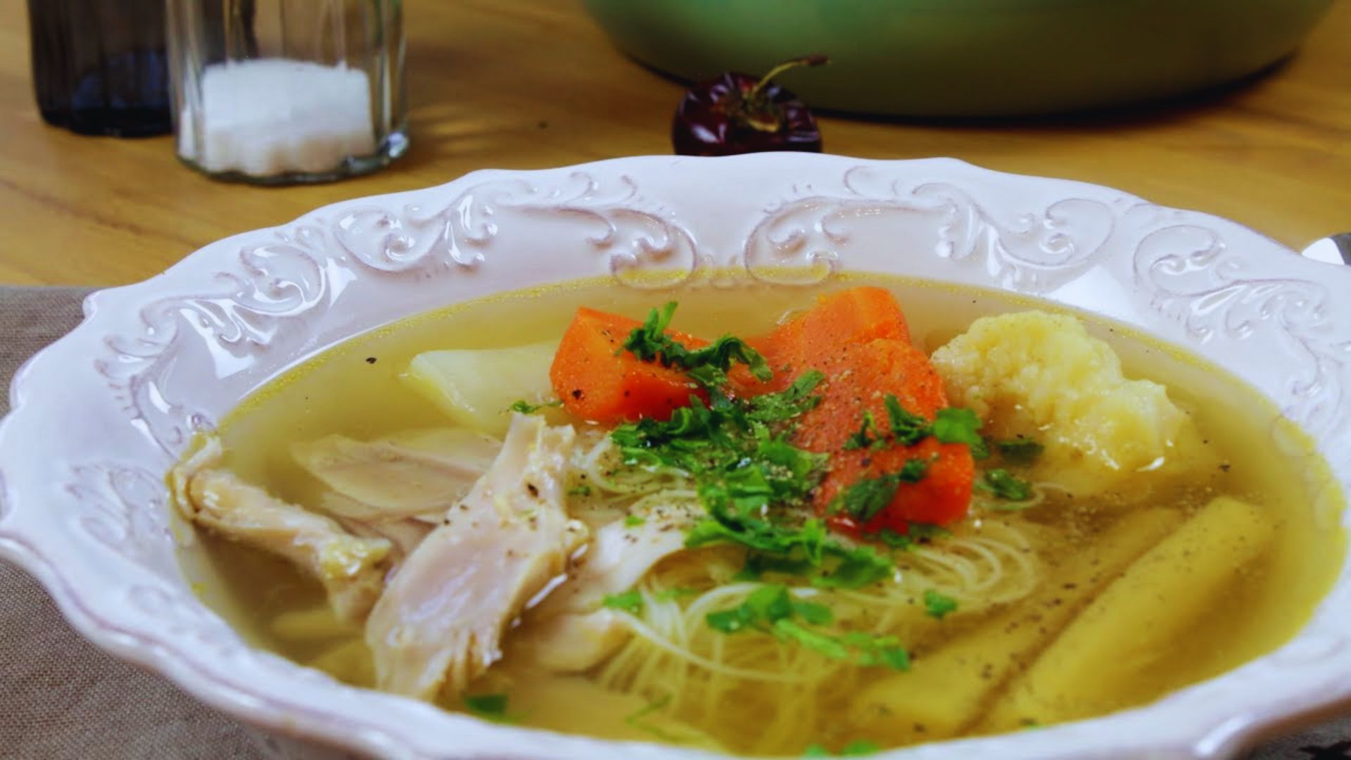 A bowl of hearty soup filled with tender meat, carrots, and potatoes, garnished with fresh herbs.