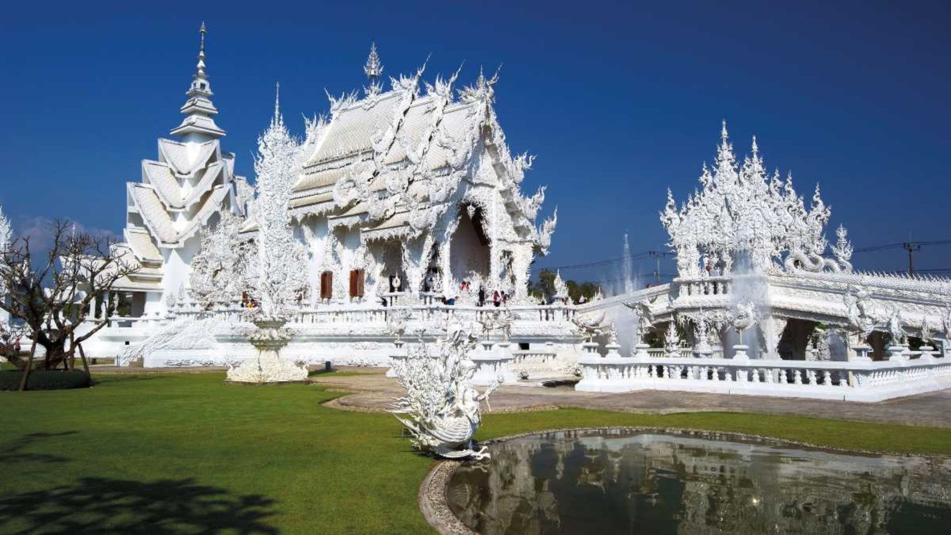 The White Temple in Chiang Rai, Thailand, features intricate white architecture and reflective pools.