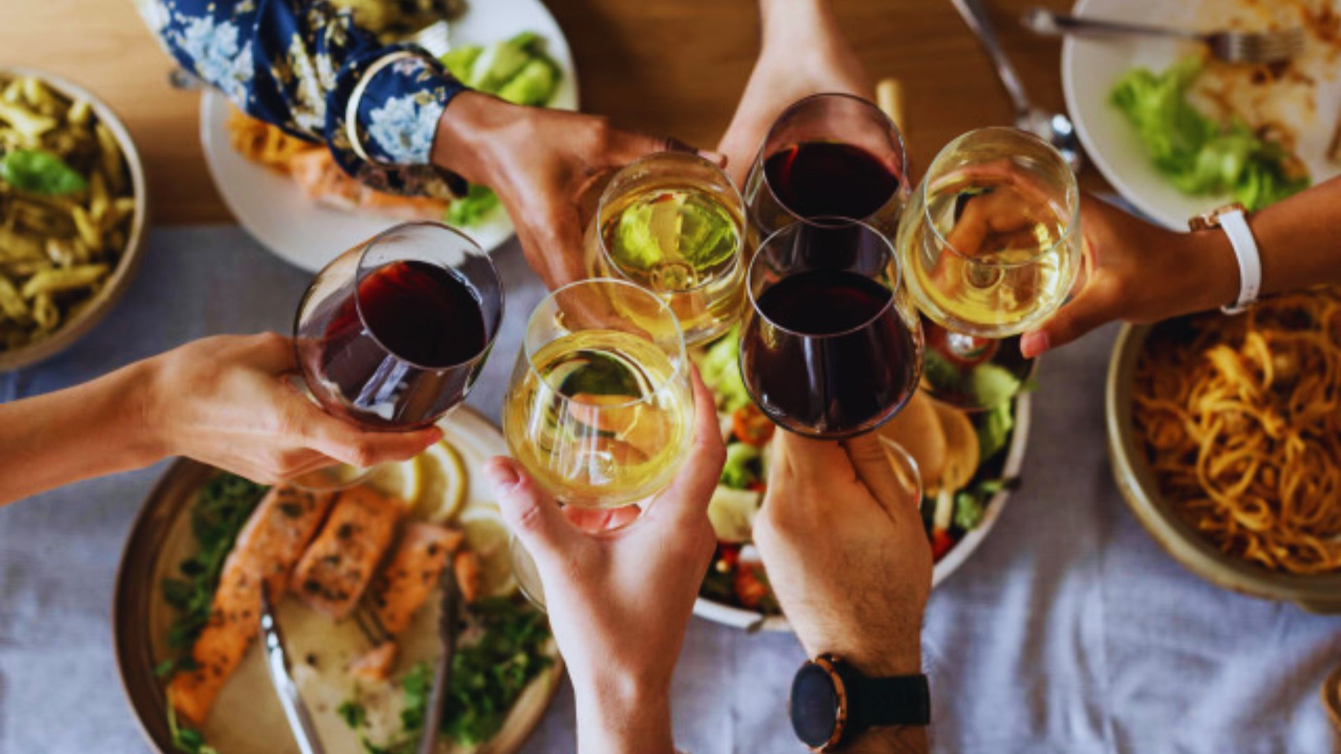 A group of people joyfully toasting with wine glasses in a celebratory setting.