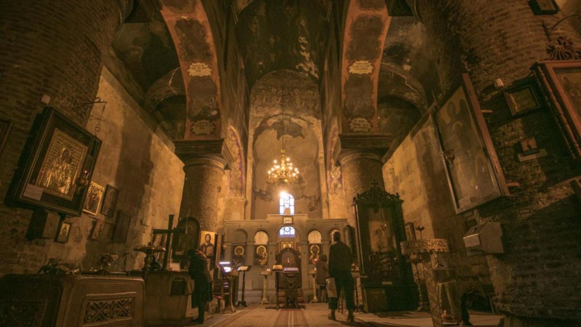Interior of an old church filled with people, showcasing historic architecture and a serene atmosphere.