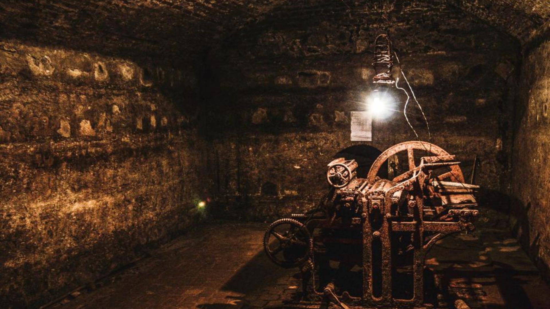 An old machine illuminated by a light in a dark tunnel, showcasing its weathered surface and surrounding shadows.