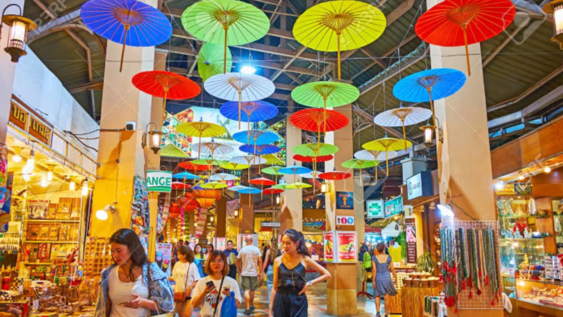 A bustling market scene with people walking under vibrant, colorful umbrellas.