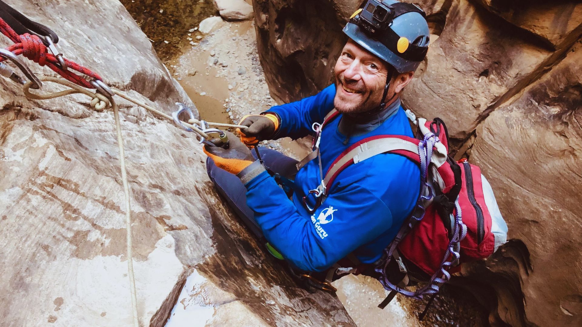 A man climbs a rocky surface in a canyon, showcasing his determination and skill in outdoor adventure.