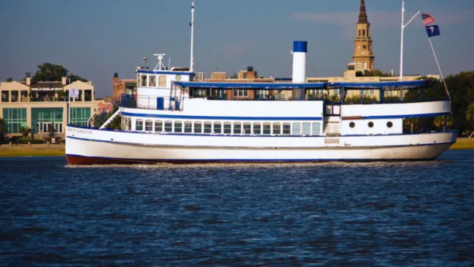A large white and blue boat floating on calm water under a clear sky.