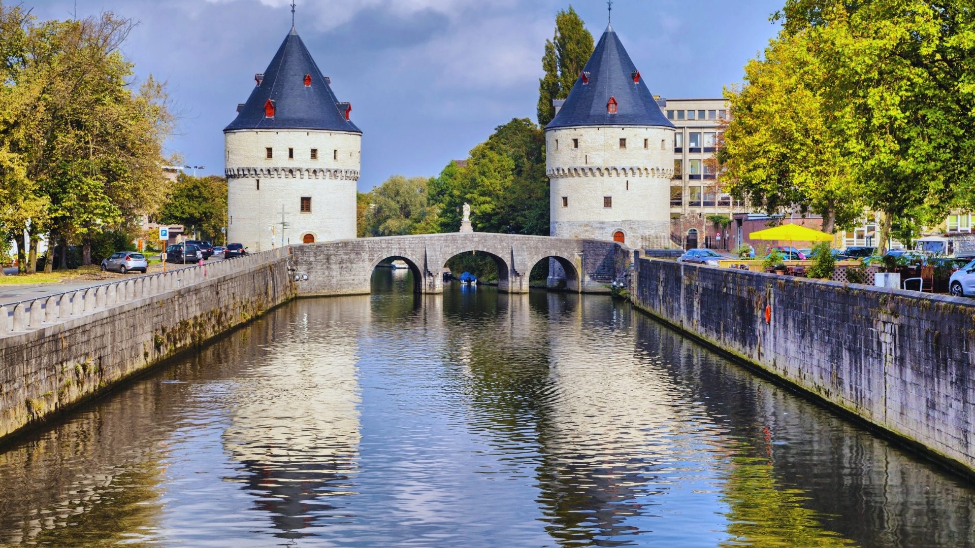 A scenic view of a canal in front of a historic castle in the city, reflecting the architecture and surrounding landscape.