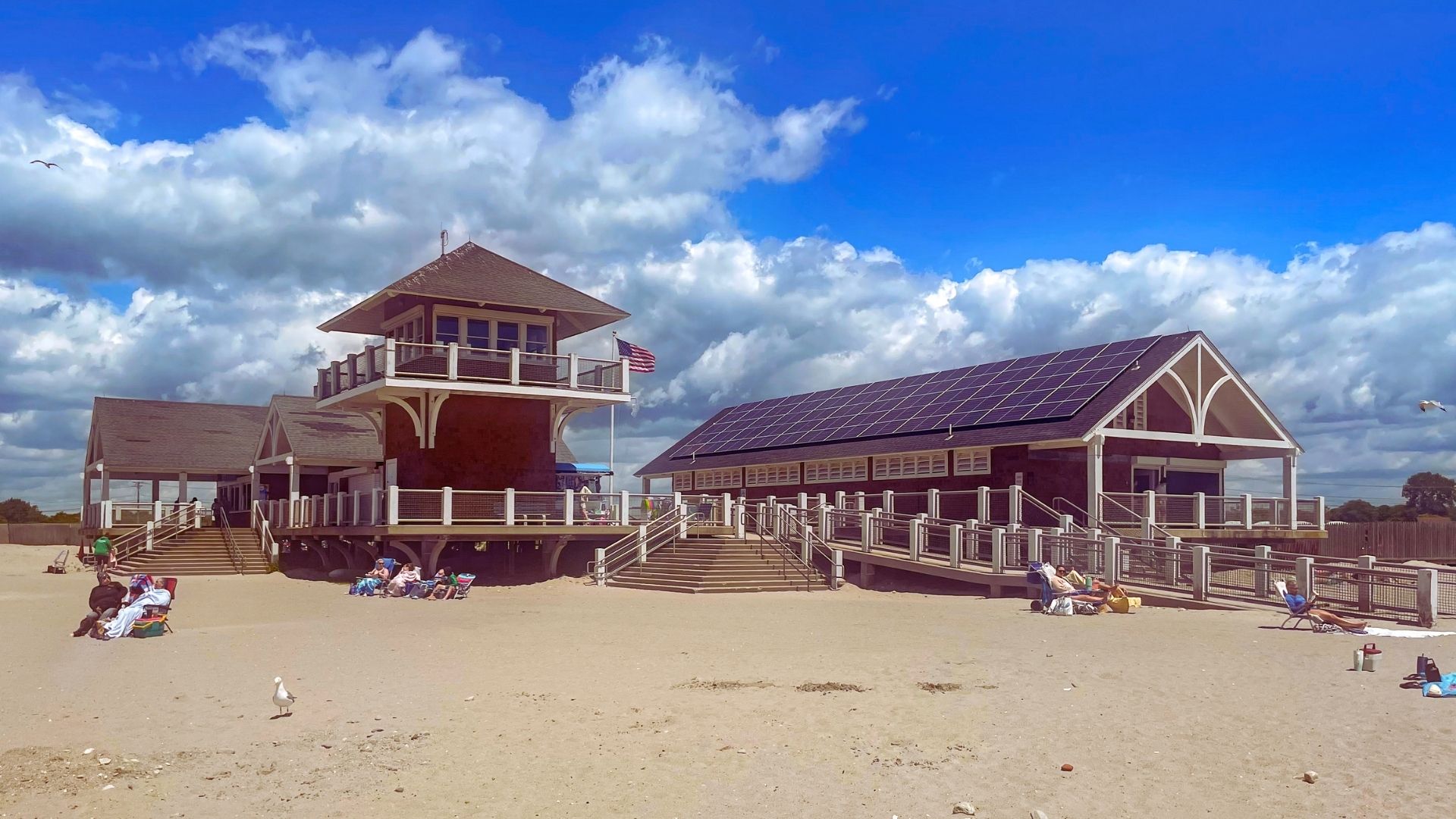 A beach scene featuring a pavilion with a roof, surrounded by sand and ocean waves in the background.