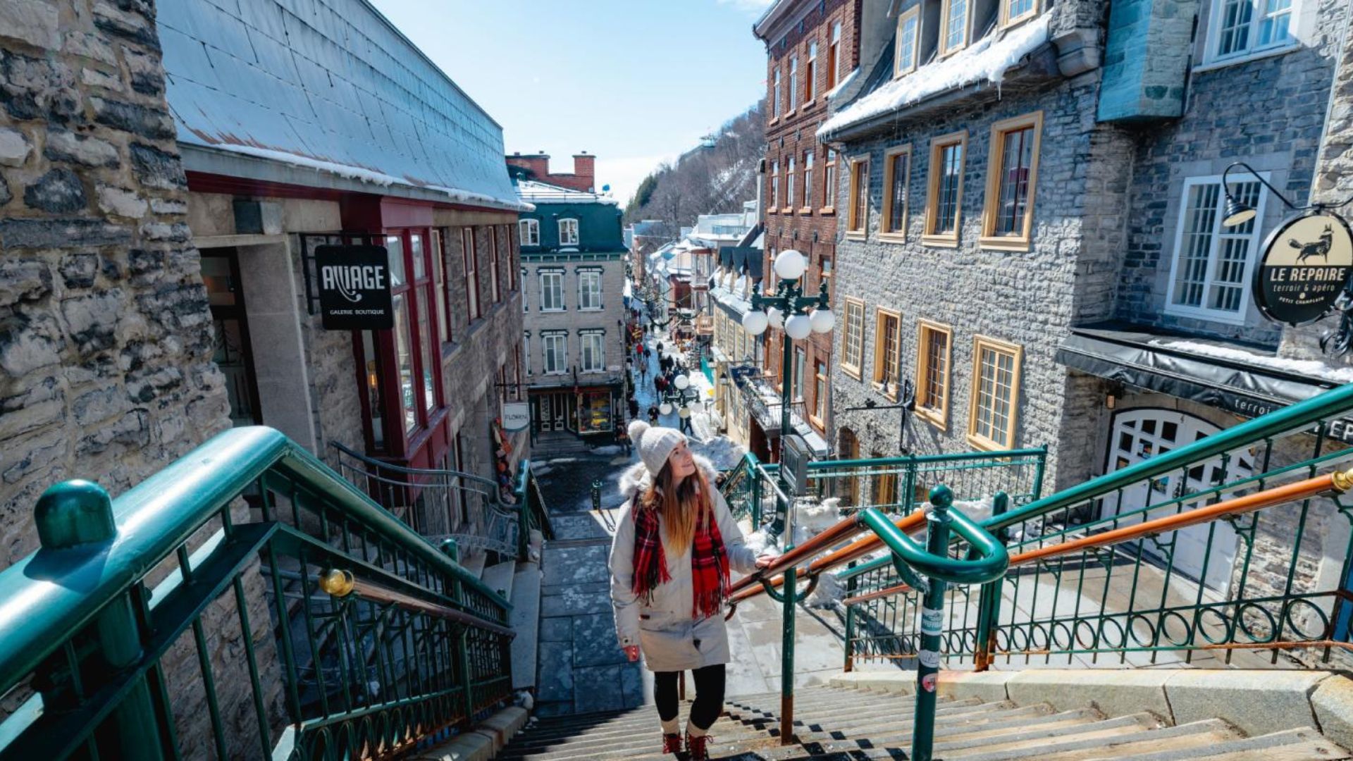 A woman ascends the stairs in the historic old town of Quebec, surrounded by charming architecture.