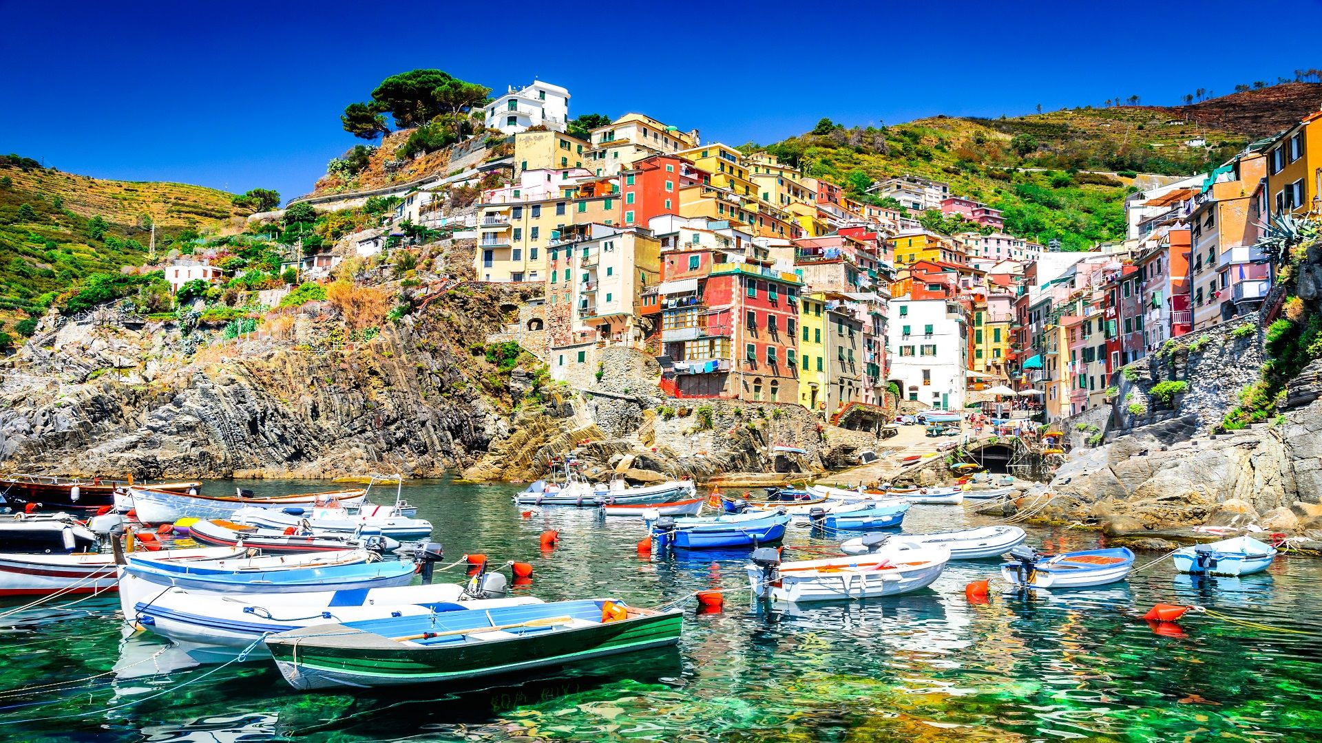 Boats are docked in the water beside vibrant, colorful buildings along the shoreline.