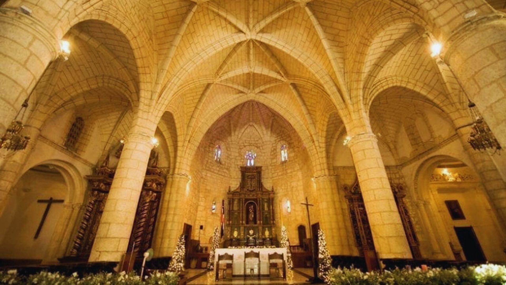 Interior view of a church featuring a large, ornate altar at the front, surrounded by wooden pews and stained glass windows.