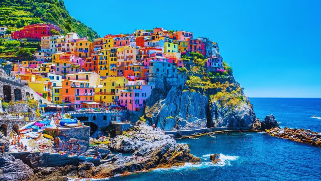 Colorful houses perched on a cliffside overlooking a serene ocean, creating a picturesque coastal scene.