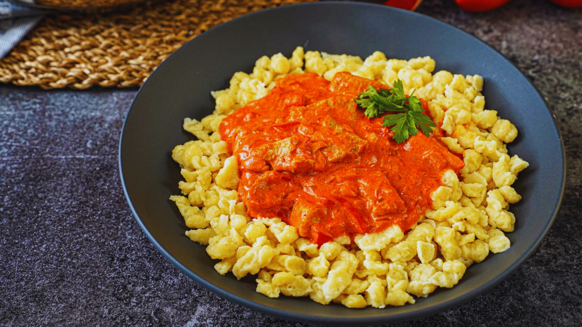 A bowl of pasta topped with rich tomato sauce and garnished with fresh parsley.