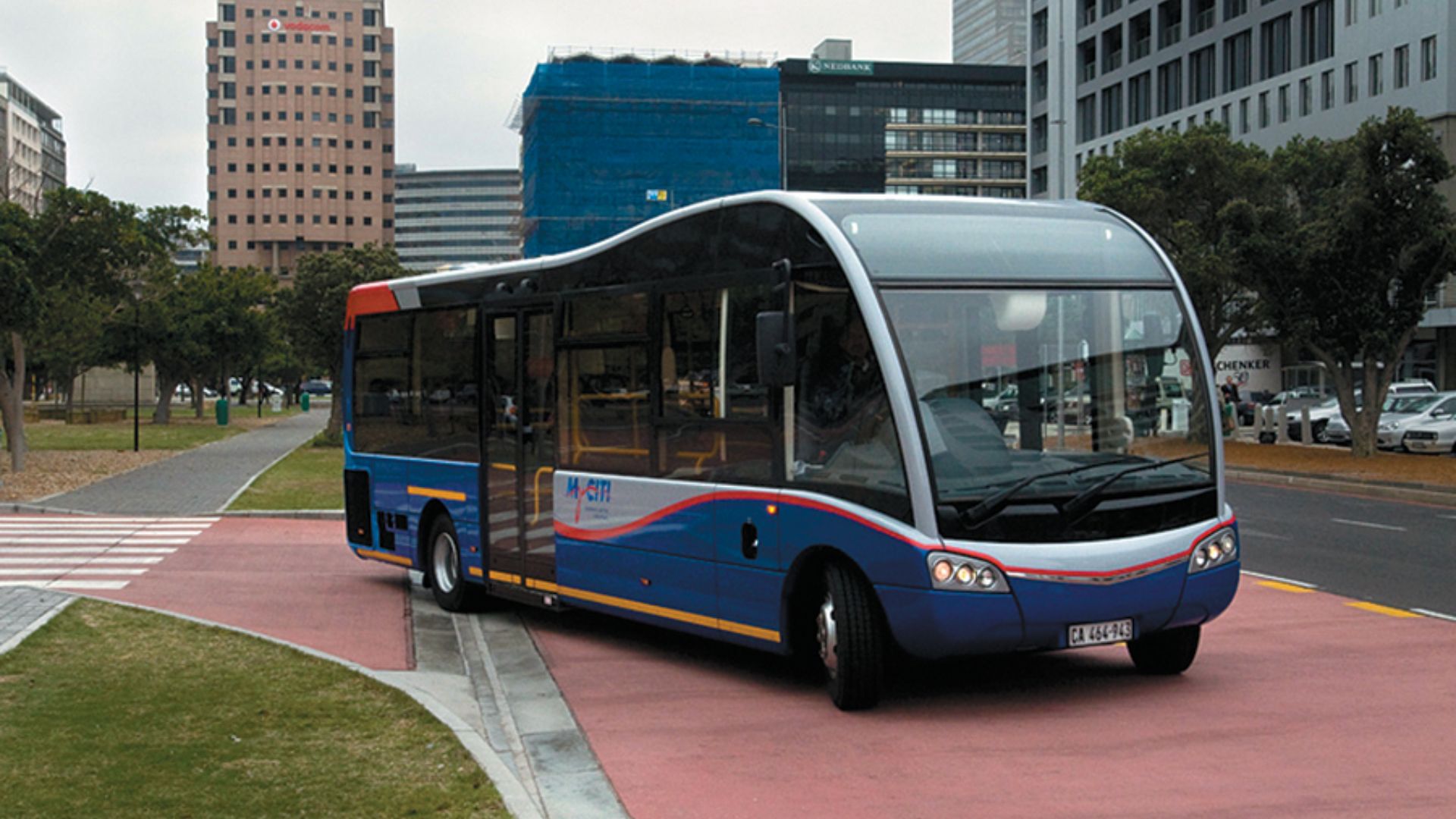 A blue and white bus parked on a bustling city street, surrounded by buildings and pedestrians.