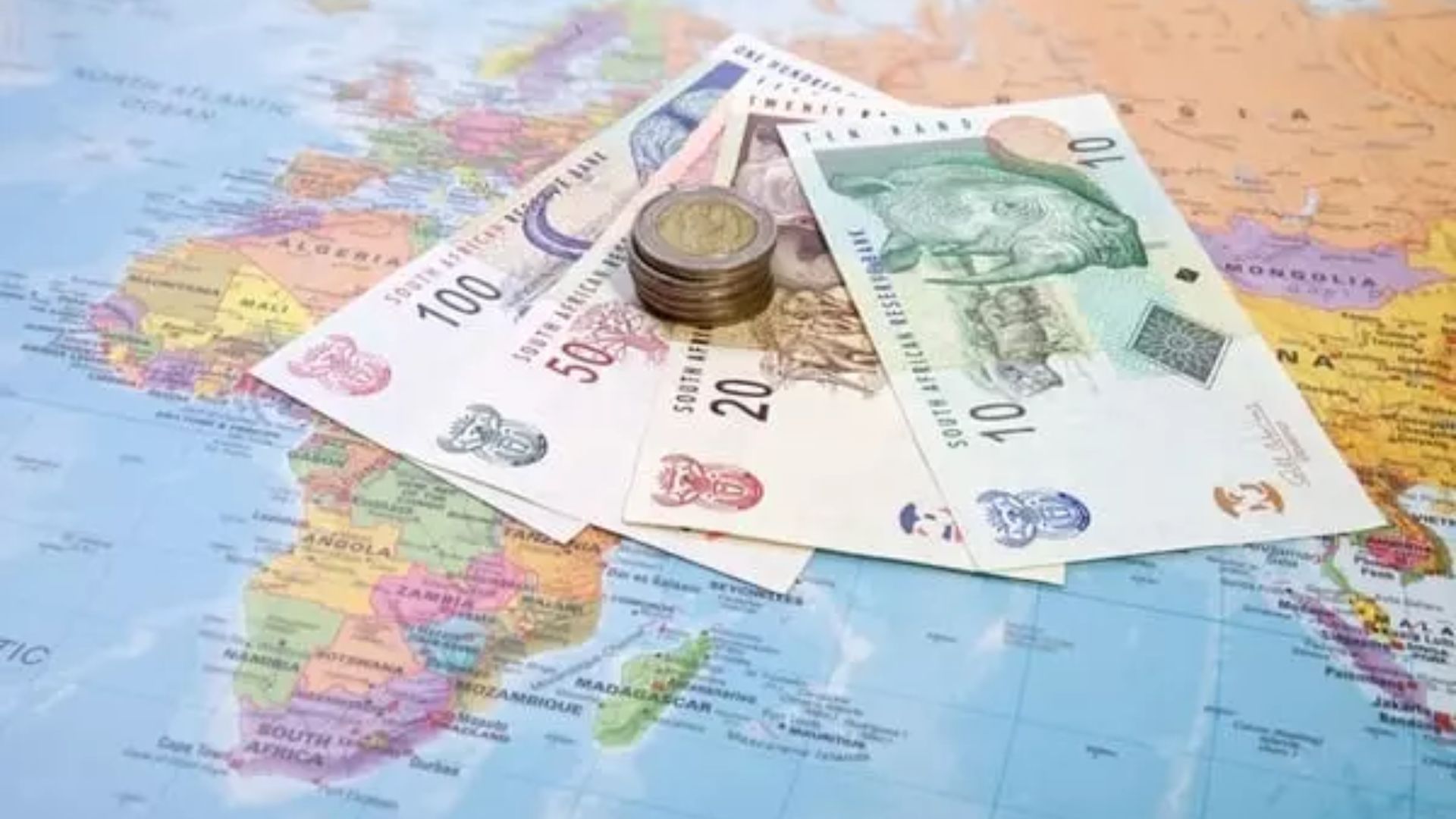 Euro currency notes and coins placed on a world map, highlighting global financial connections.