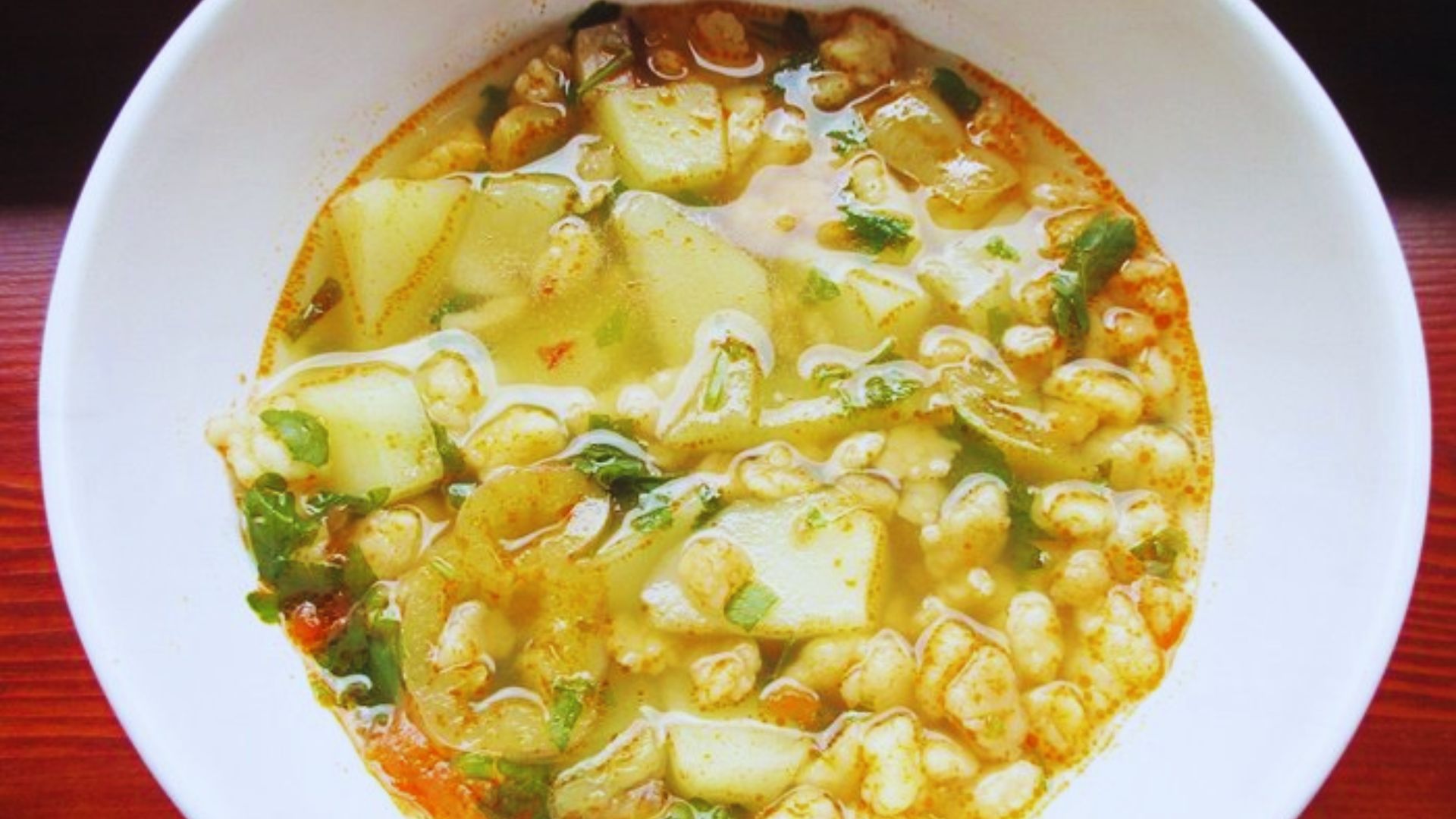 A bowl of hearty soup filled with assorted vegetables and tender pieces of meat.