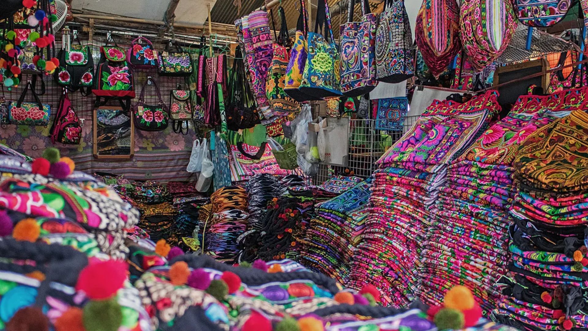 A vibrant market display featuring an array of colorful bags and purses in various styles and patterns.