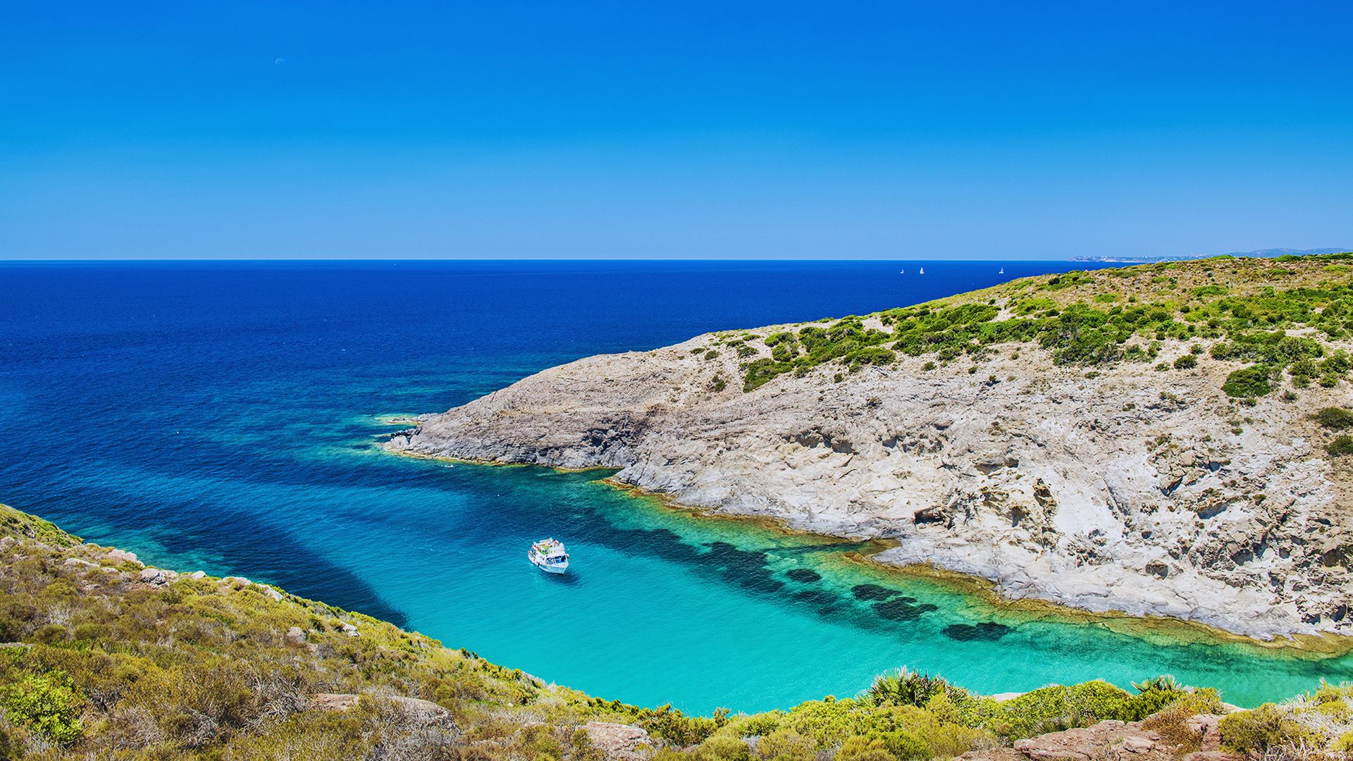 A serene coastal scene with vibrant turquoise water nestled between rocky cliffs, a small boat anchored, and a clear blue sky overhead, evoking tranquility.