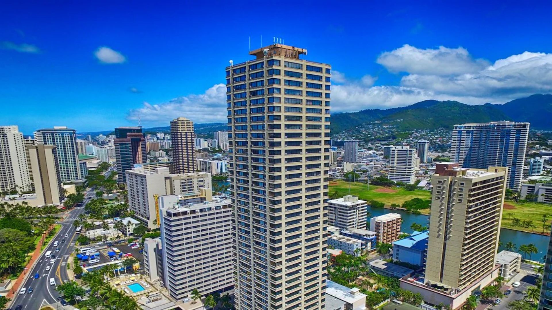 A panoramic view of the Honolulu skyline from a high-rise building, showcasing skyscrapers against a clear blue sky.