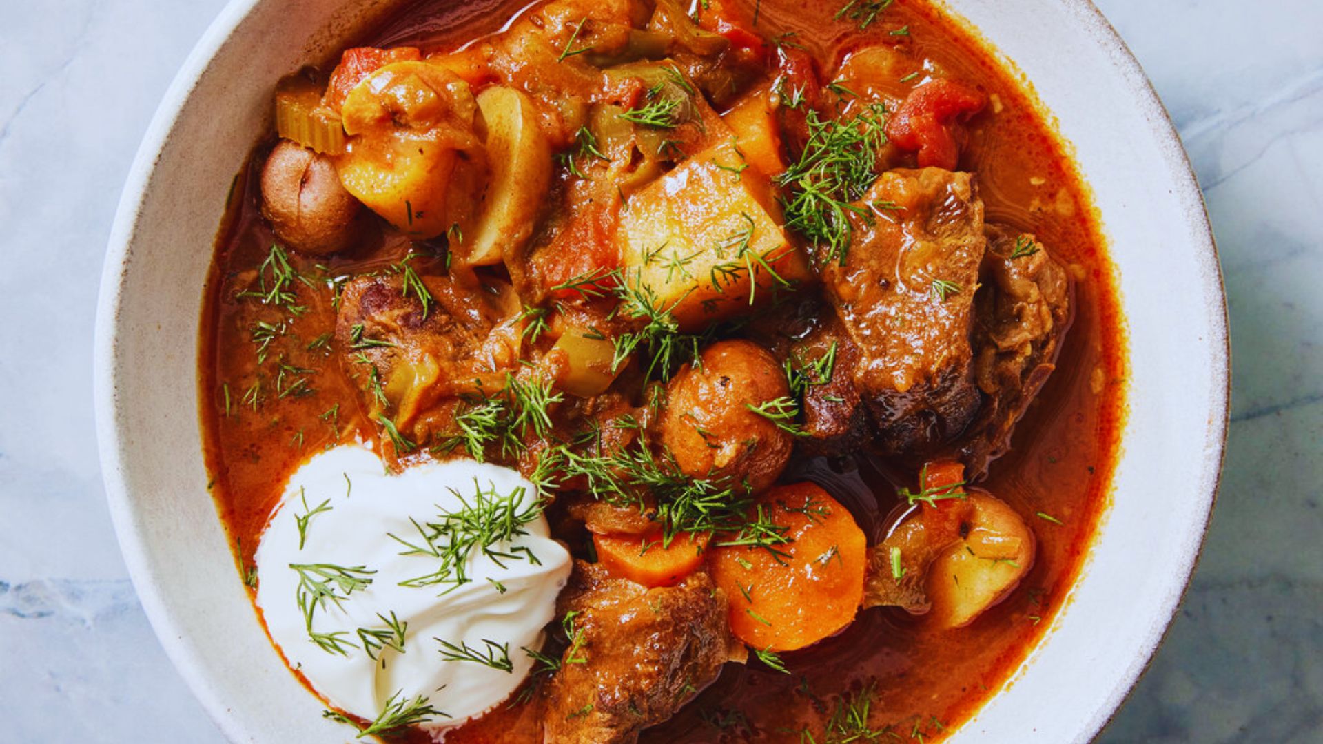 A colorful bowl of Kiev borscht garnished with herbs, showcasing beets, cabbage, and a dollop of sour cream.