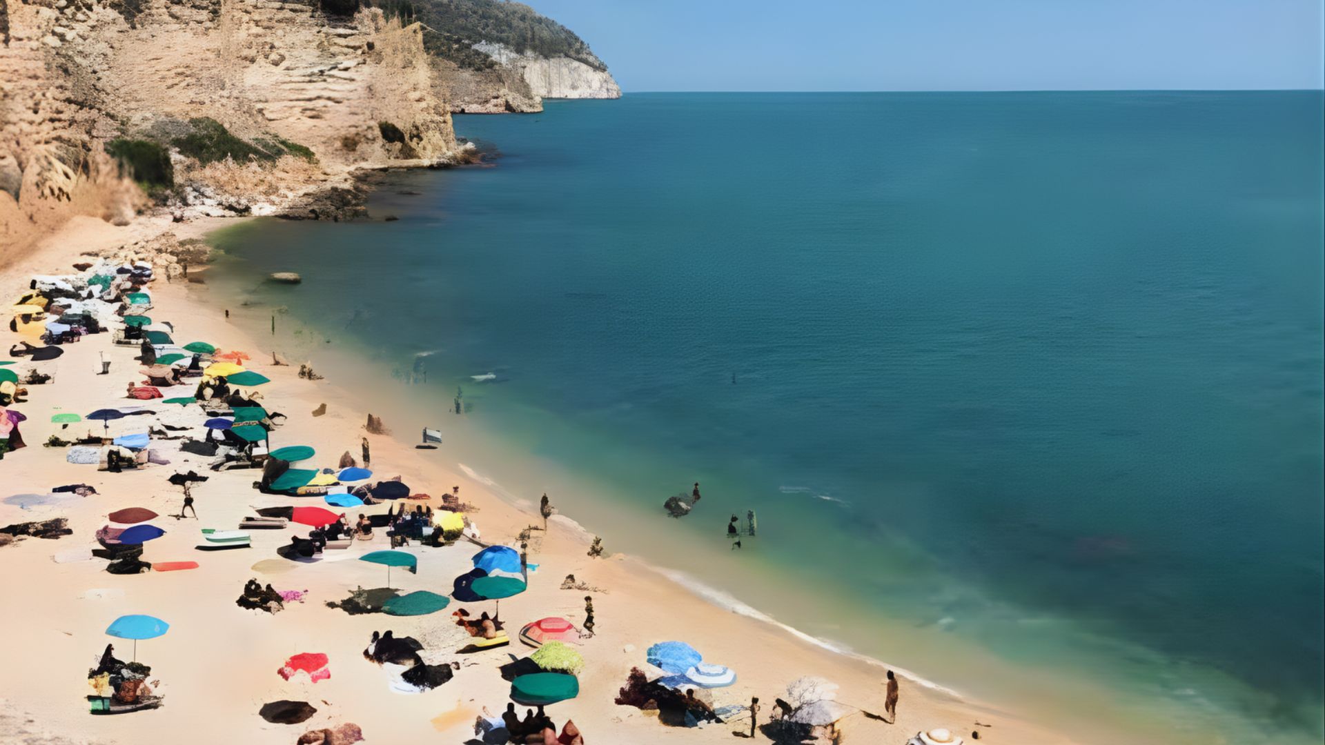 A vibrant beach scene with colorful umbrellas scattered across golden sand. People relax, swim, and enjoy the sunny day by calm, blue-green ocean waters.