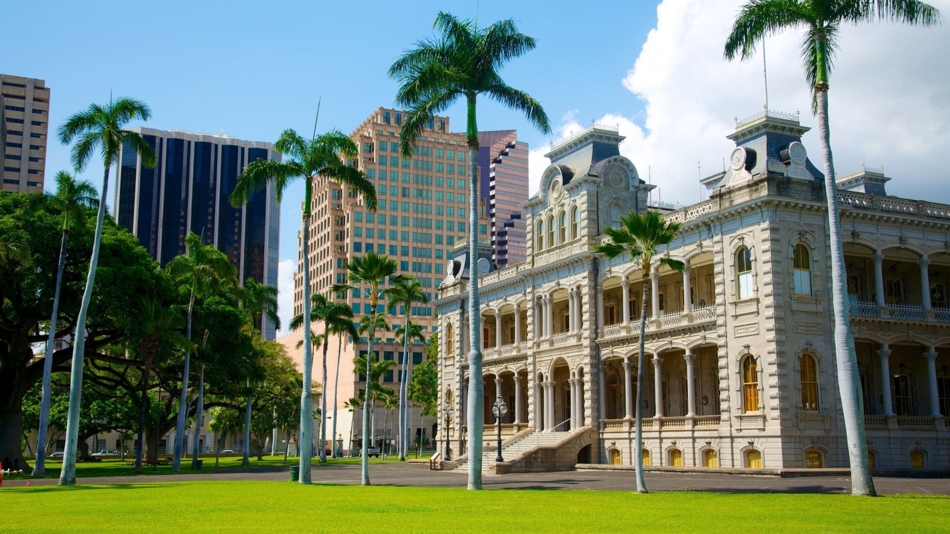 Honolulu City Hall, a historic building featuring Hawaiian architecture, surrounded by palm trees and a clear blue sky.