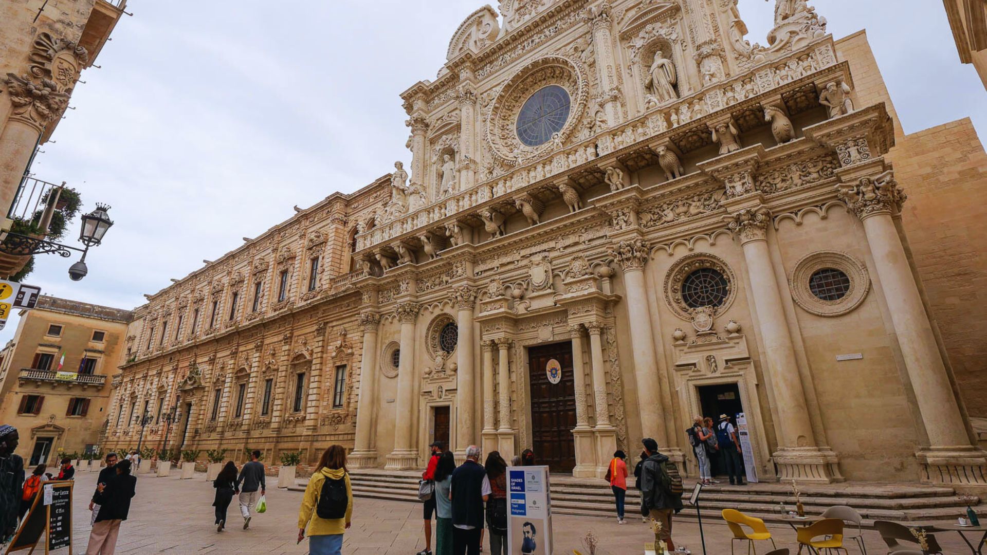 A group of people walking in front of a large building, showcasing urban activity and architectural presence.