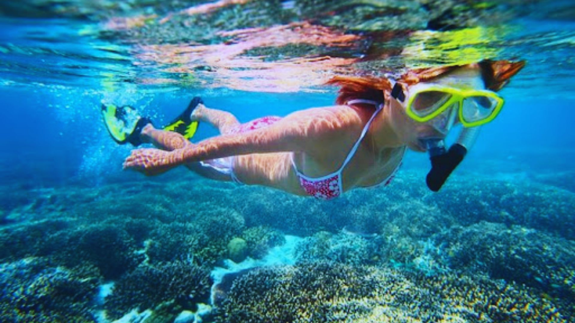 A woman snorkeling in the ocean, wearing a mask and exploring underwater life.
