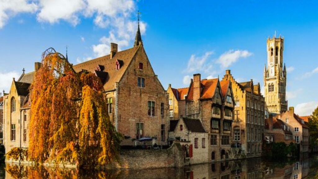 Scenic view of Bruges, Belgium, showcasing its historic architecture and picturesque canals under a clear blue sky.