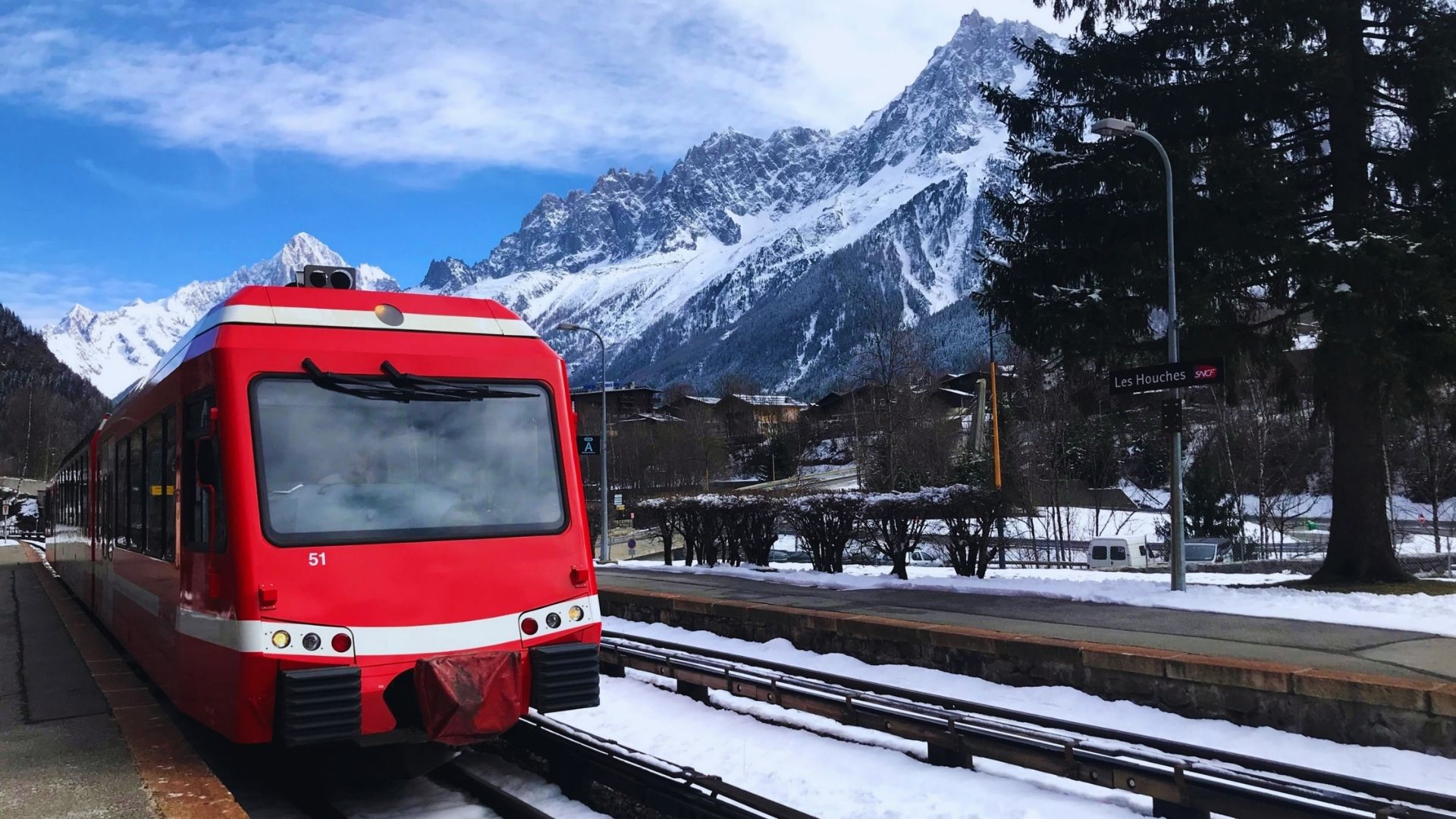 A red train stands still at the station, ready for its next journey.