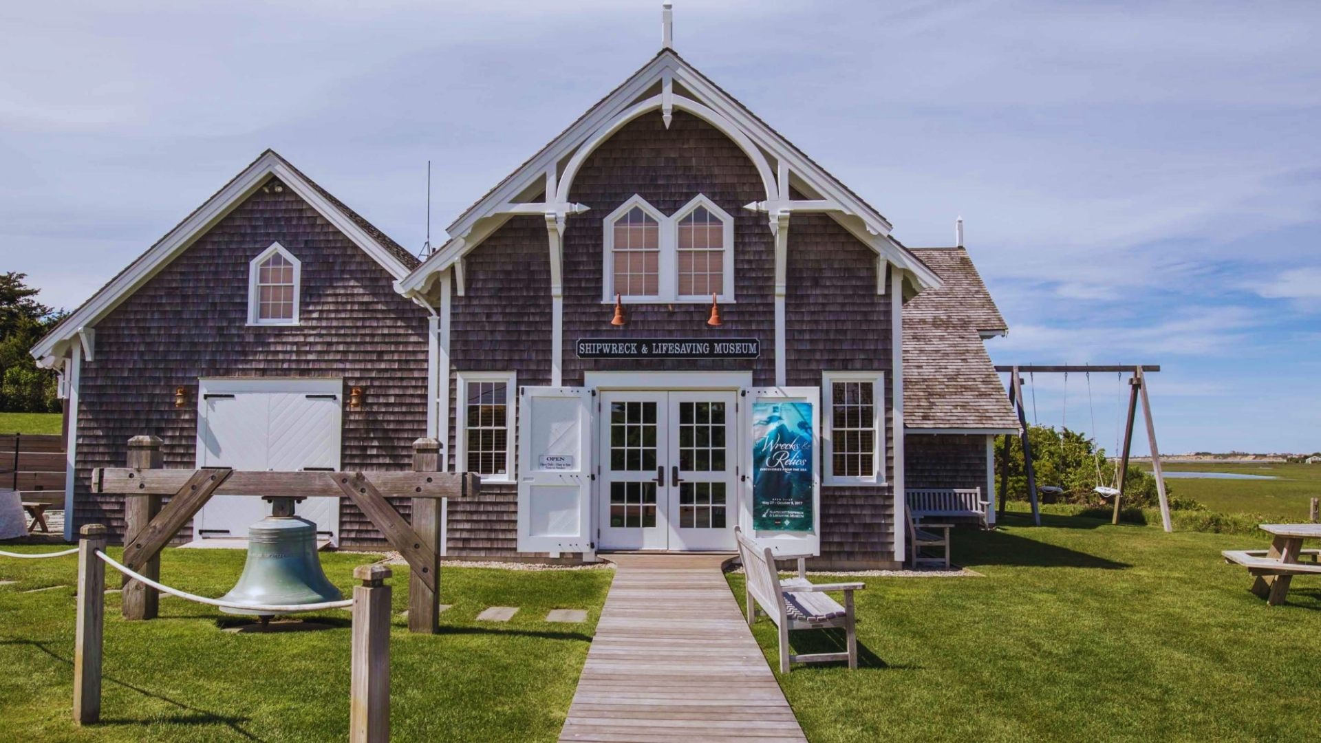 The historic barn at the Cape Cod Museum of Natural History, surrounded by greenery and a clear blue sky.