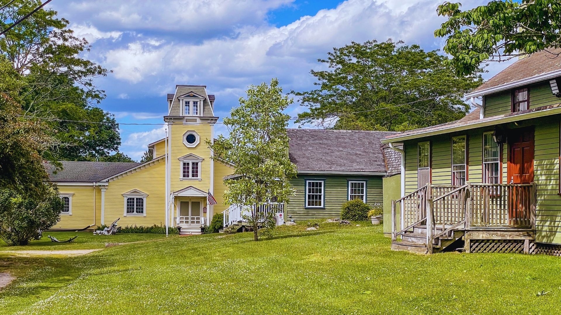 A yellow house featuring a prominent steeple at the front, set against a clear blue sky.